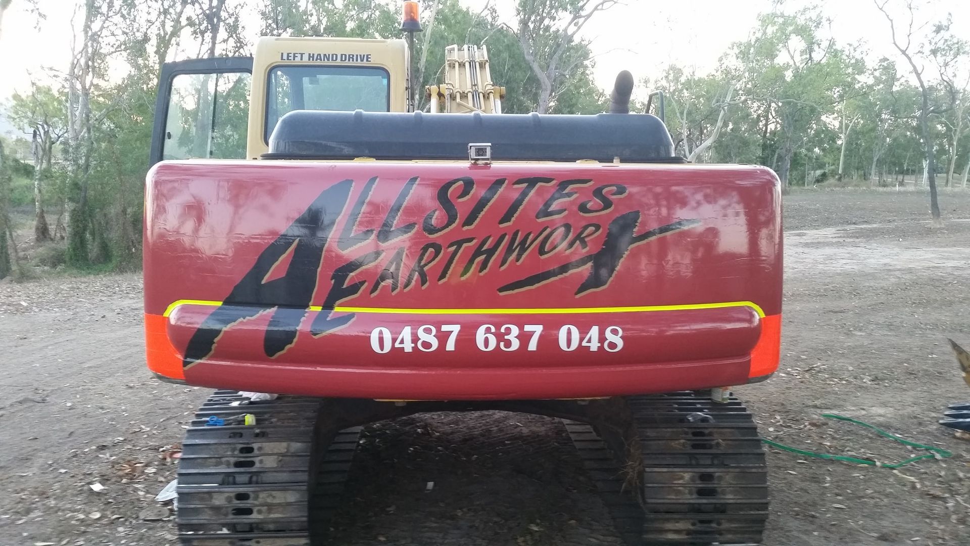 A Red Allsites Earthworx Excavator Is Parked In A Dirt Field — Allsites Earthworx In Garbutt, QLD