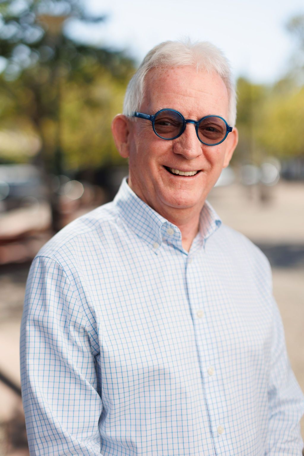 A man in a purple shirt is smiling in front of a sign.