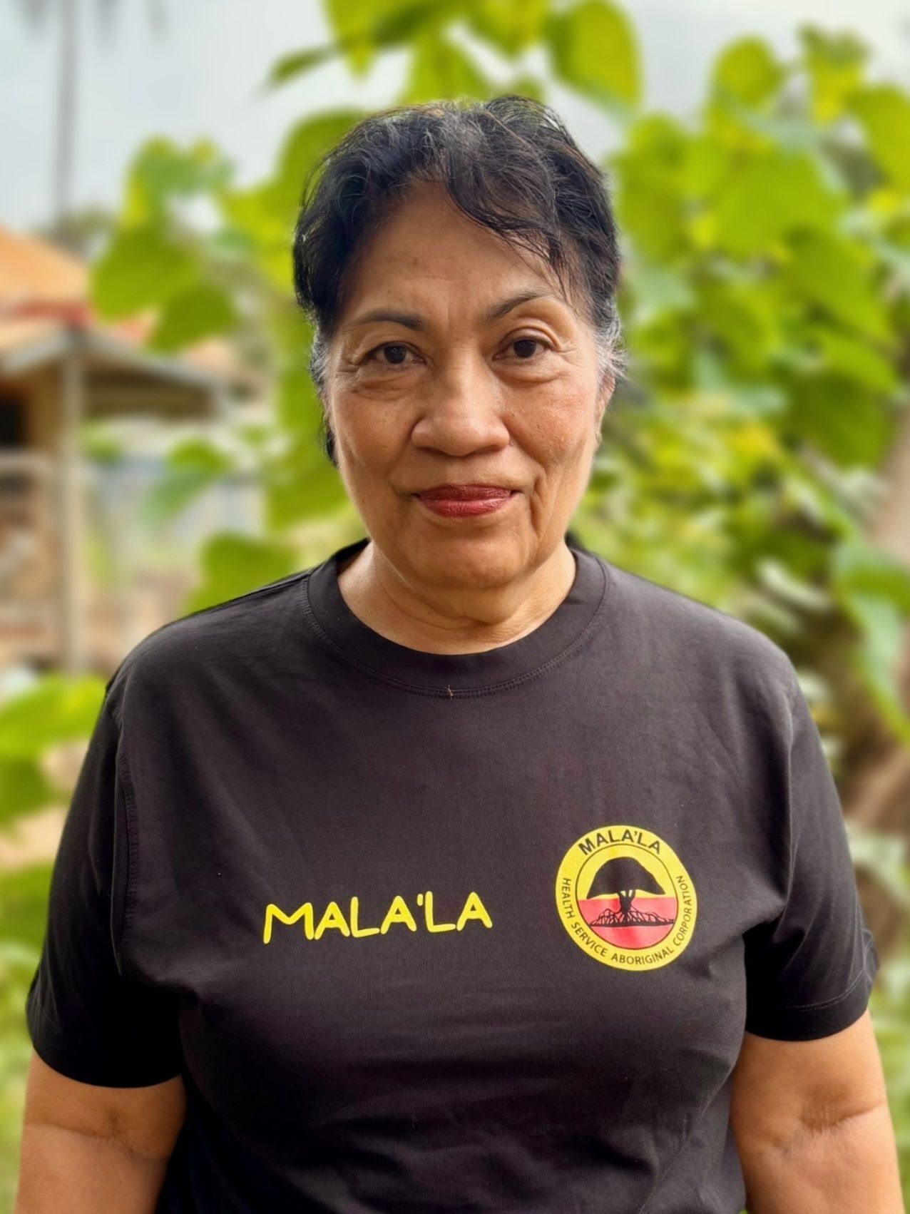 A woman wearing glasses and a colorful shirt is smiling for the camera.