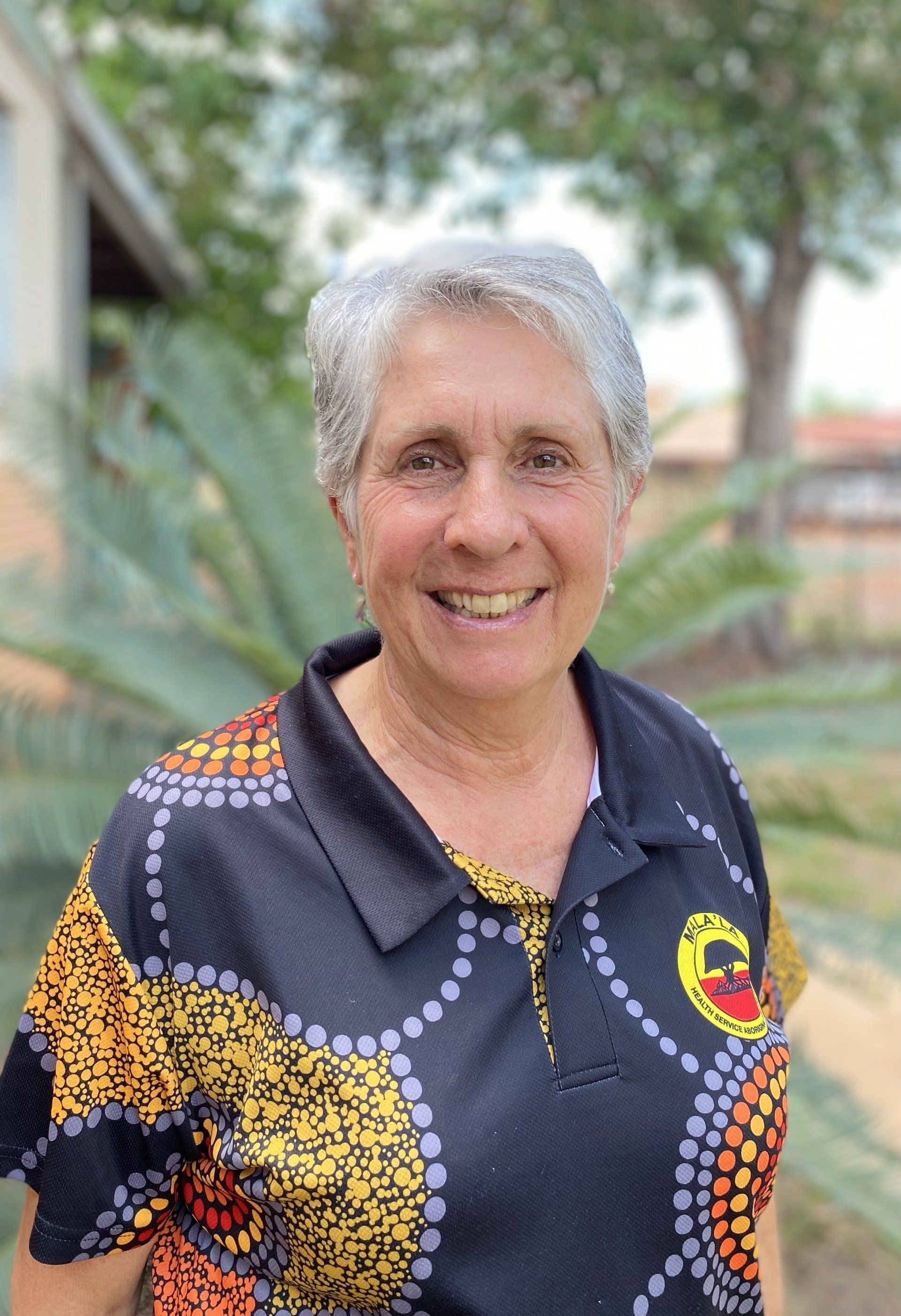 A woman in a colorful shirt is smiling for the camera.