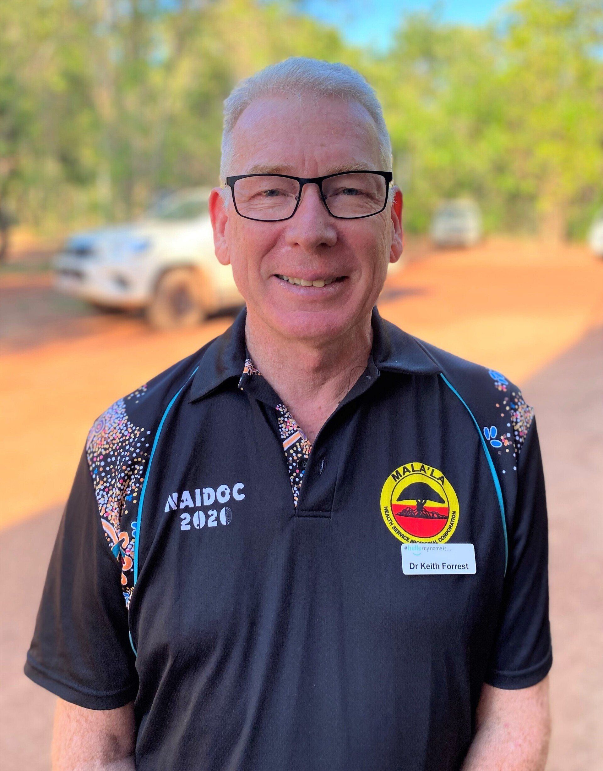 A man wearing glasses and a black shirt is smiling for the camera.