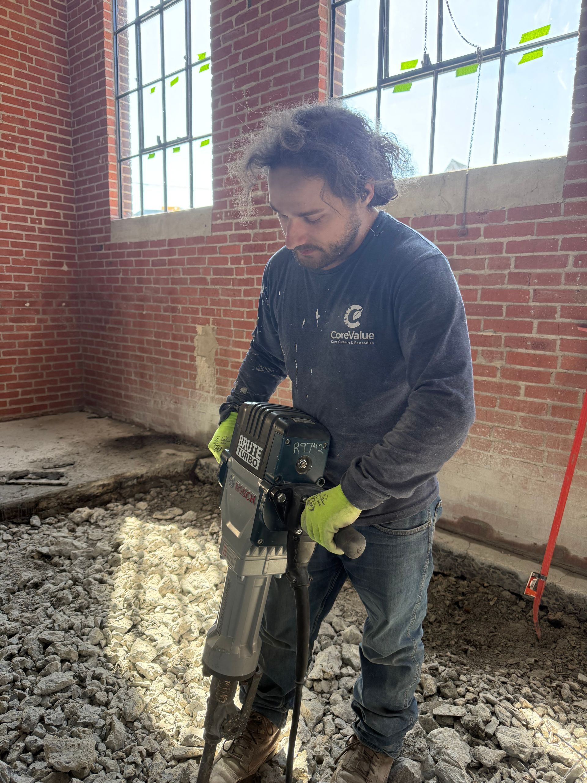 Man in blue uniform smiles, holding a clipboard and pen indoors.