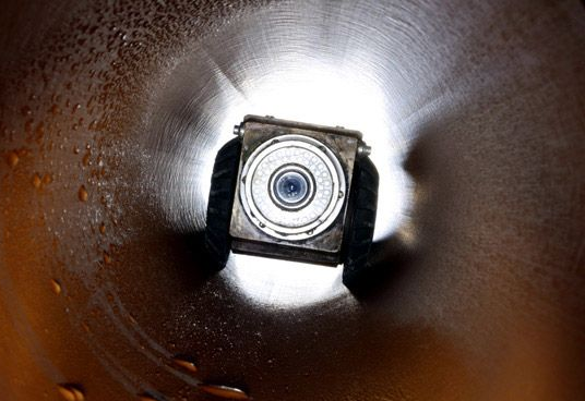 A camera inside a shiny, cylindrical tube, looking toward the bright opening.