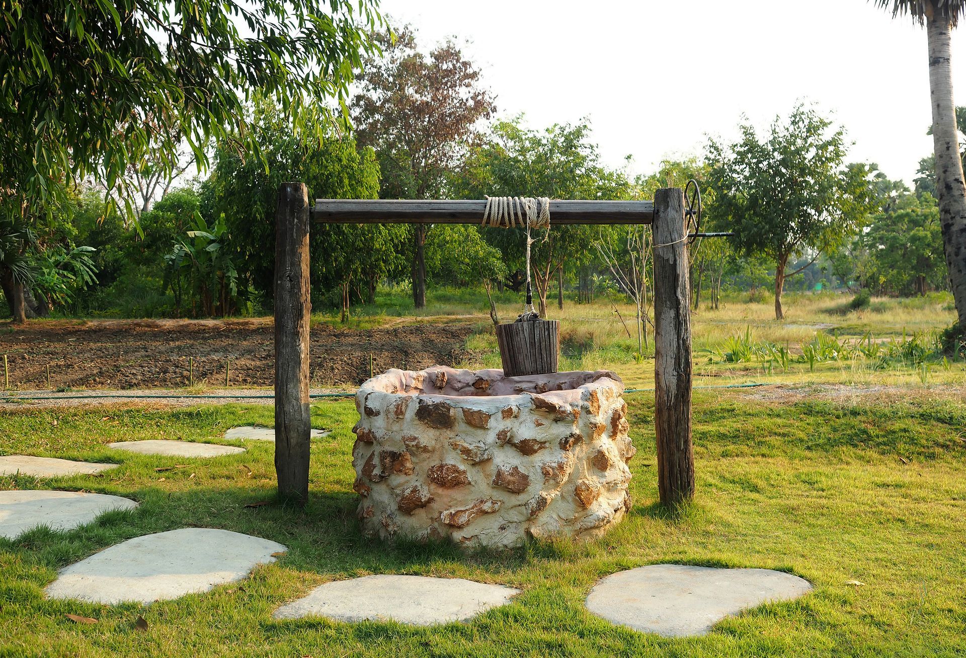 A basket tied to a wooden arch surrounding a well, complementing a well water filtration system.