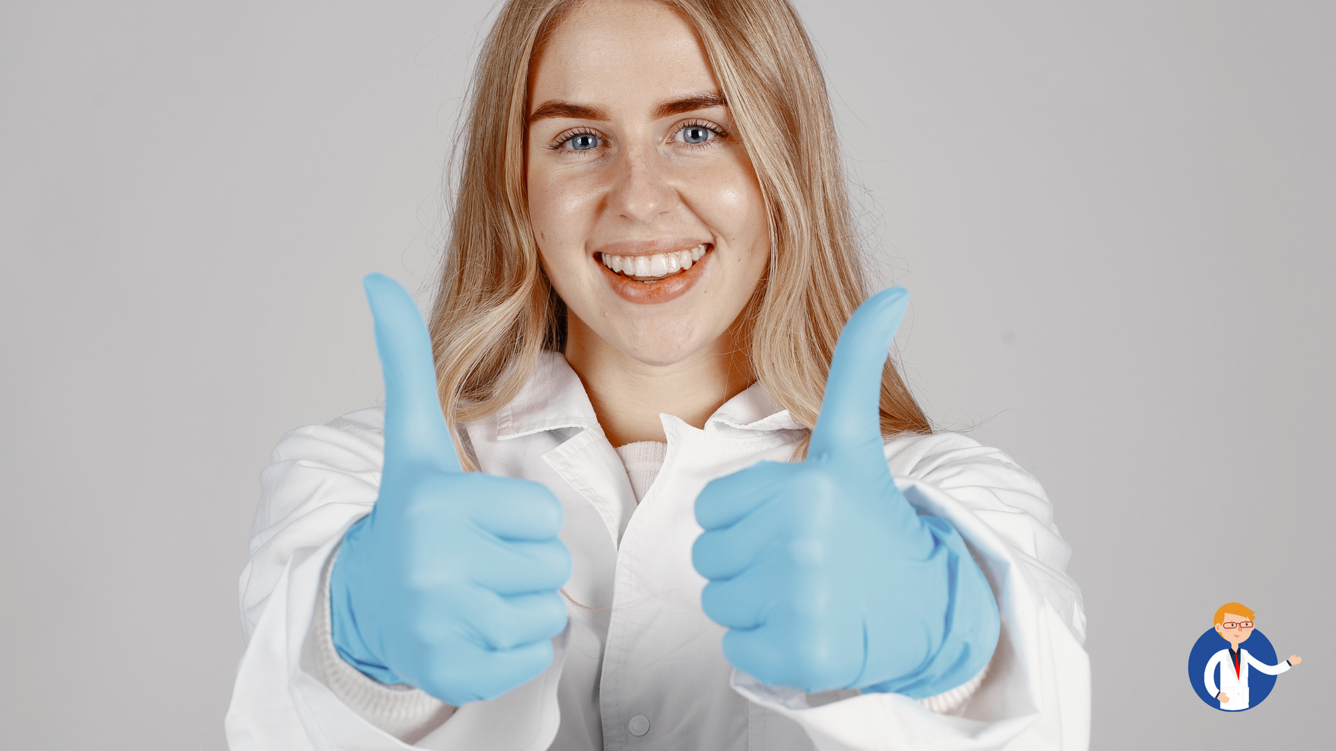 A woman in a lab coat and blue gloves is giving two thumbs up.