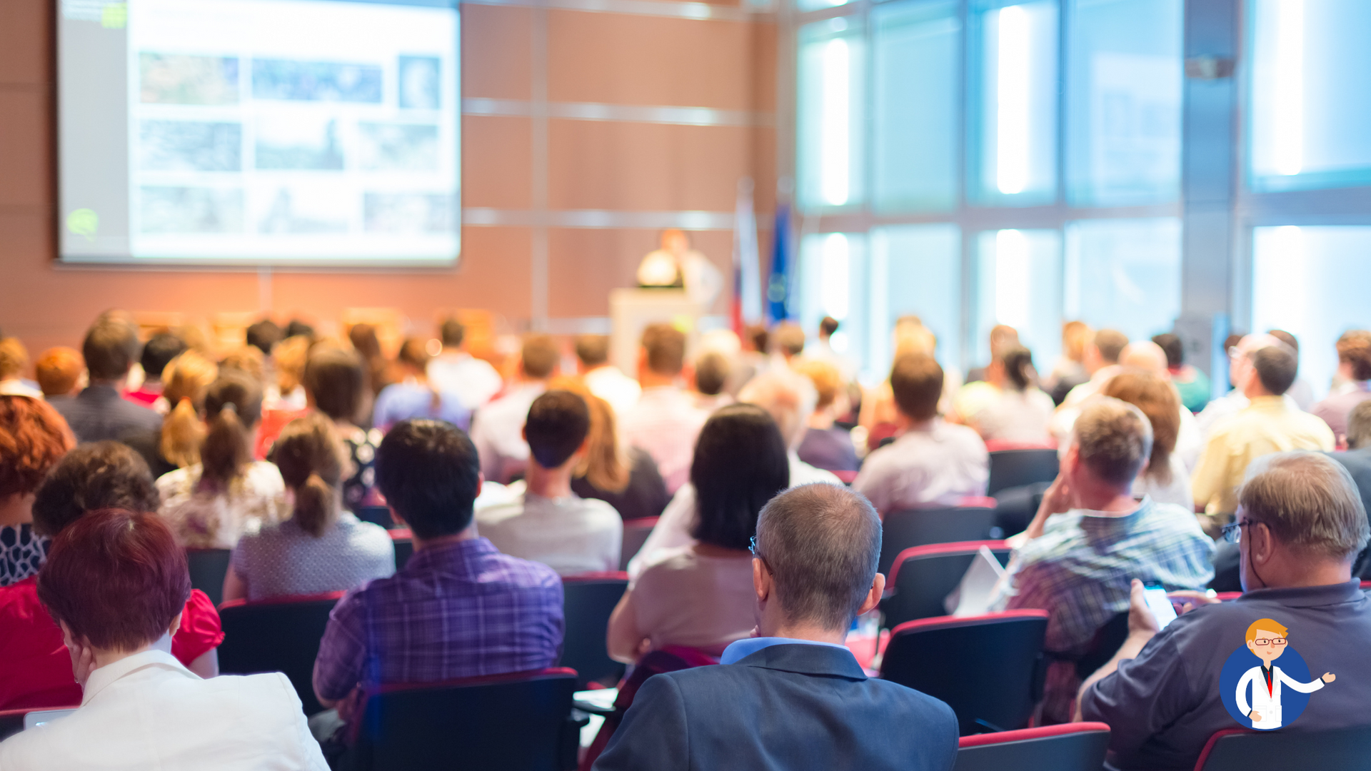 A large group of people are sitting in a conference room watching a presentation.