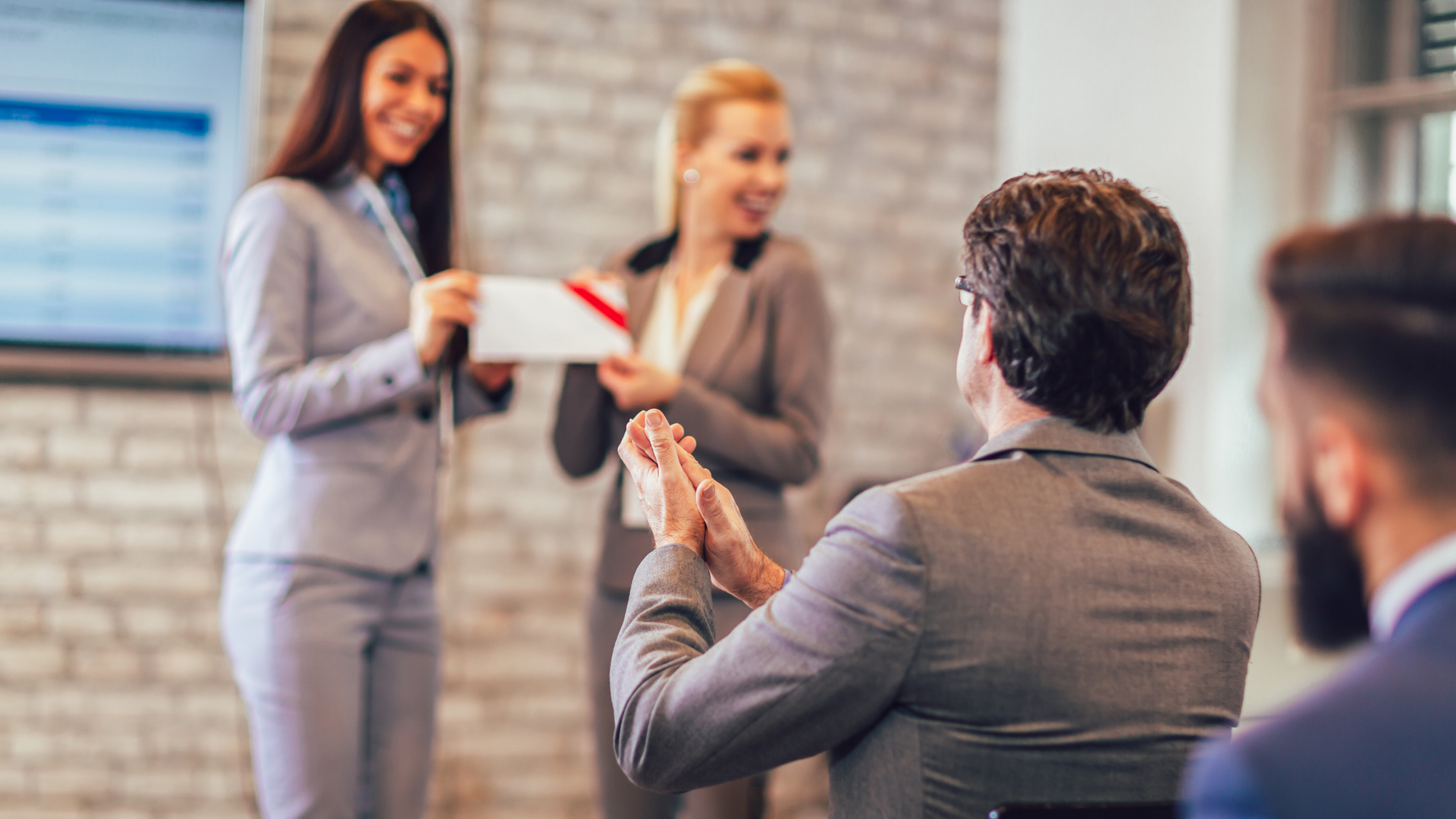A group of business people are clapping their hands in a conference room.