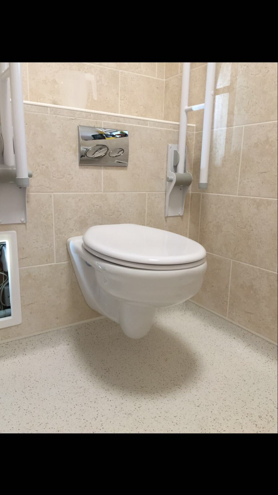 A toilet is hanging from the wall in a bathroom.