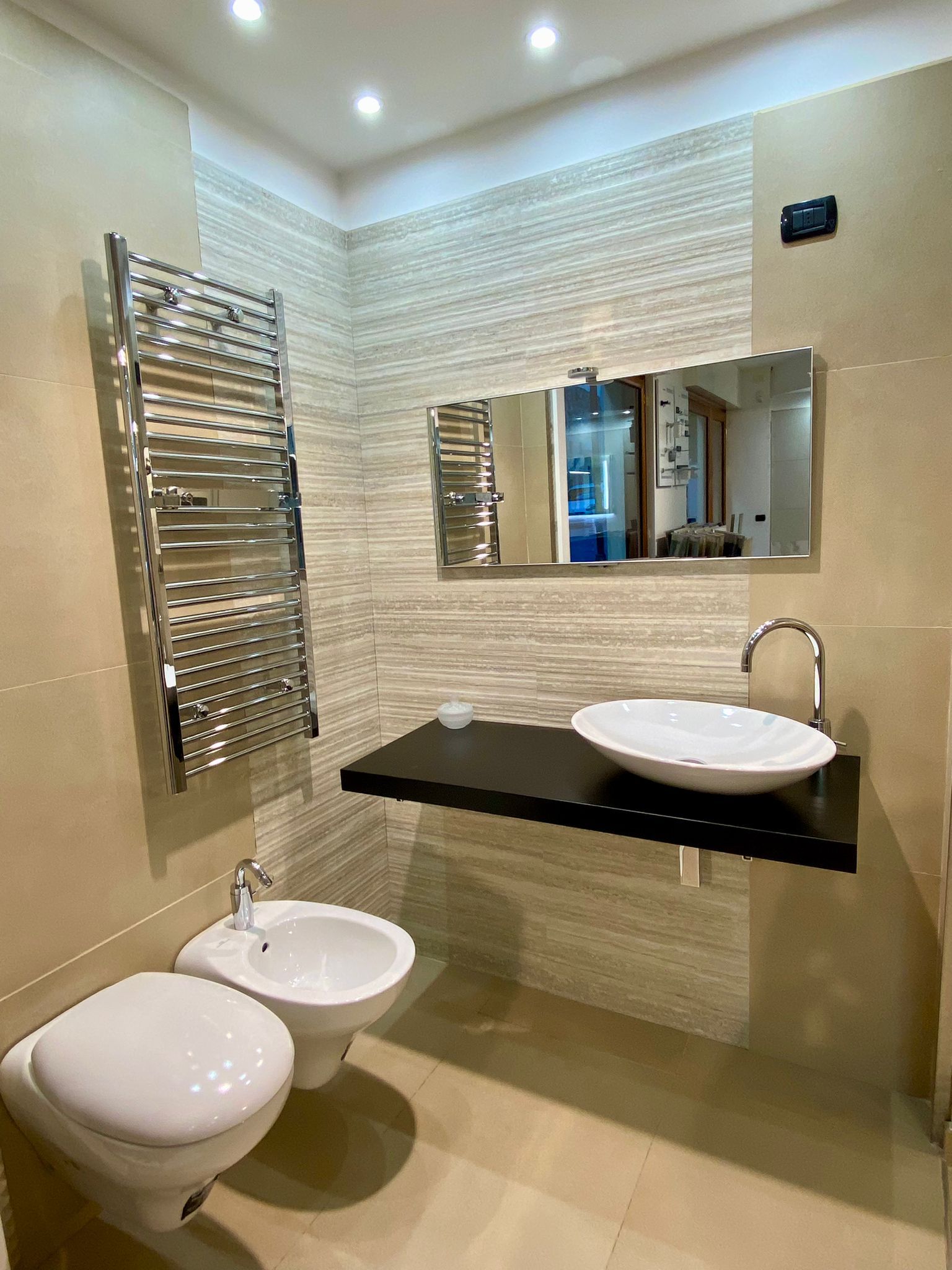 Un bagno con wc, bidet, lavabo e specchio.