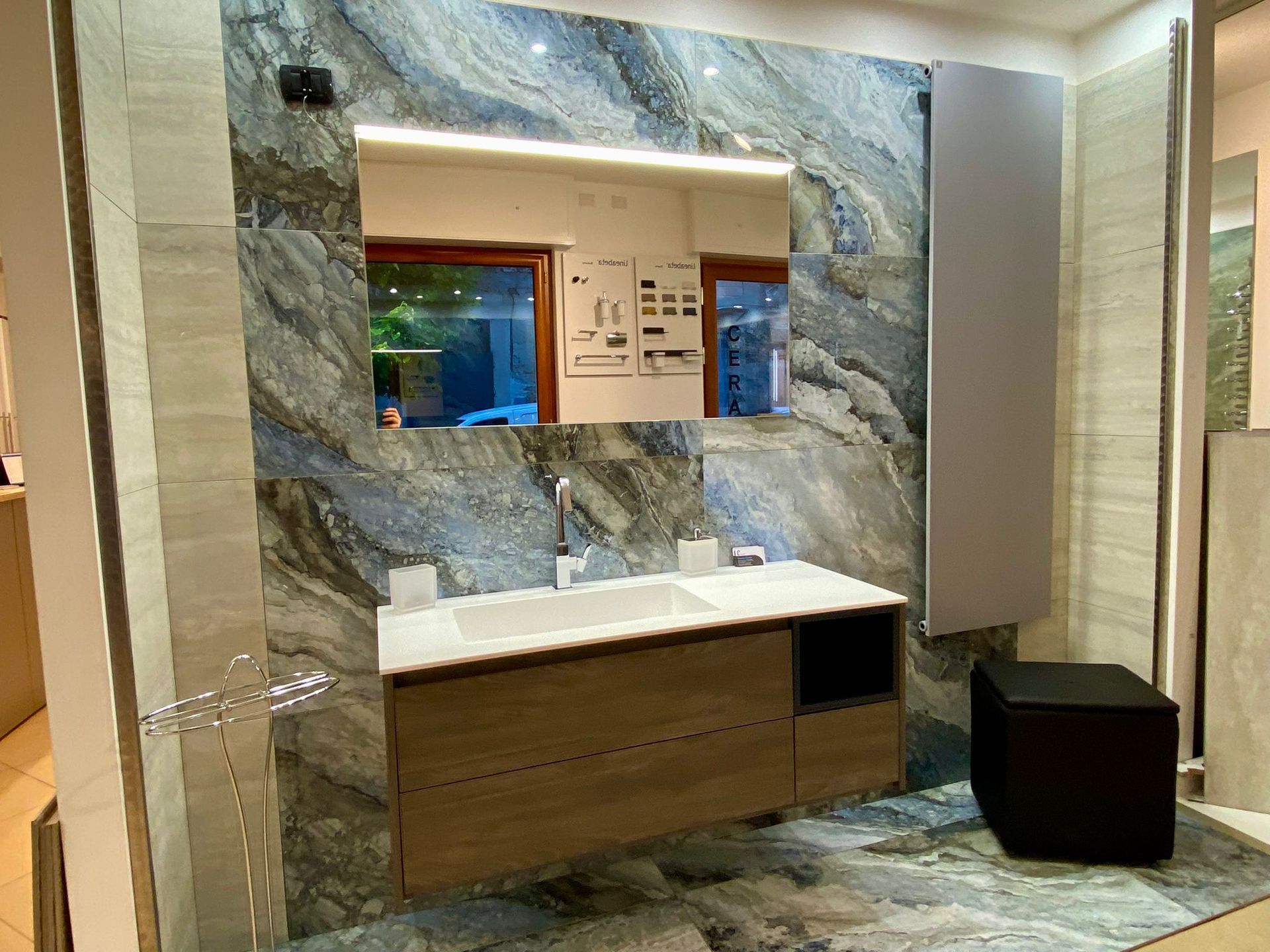 Un bagno con lavabo, specchio, mobiletto e pattumiera.