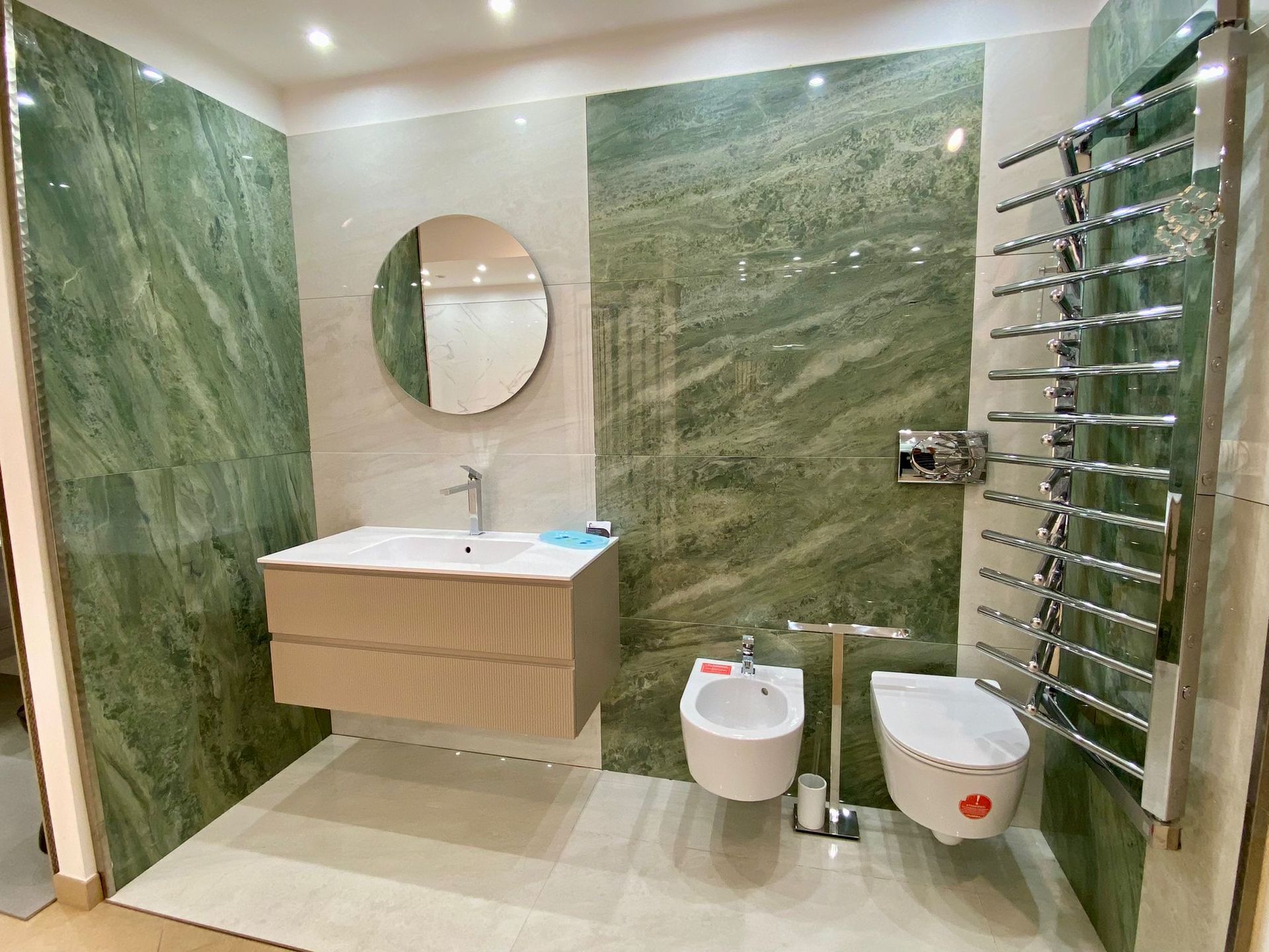 Un bagno con piastrelle verdi, un lavandino, un wc e uno specchio.