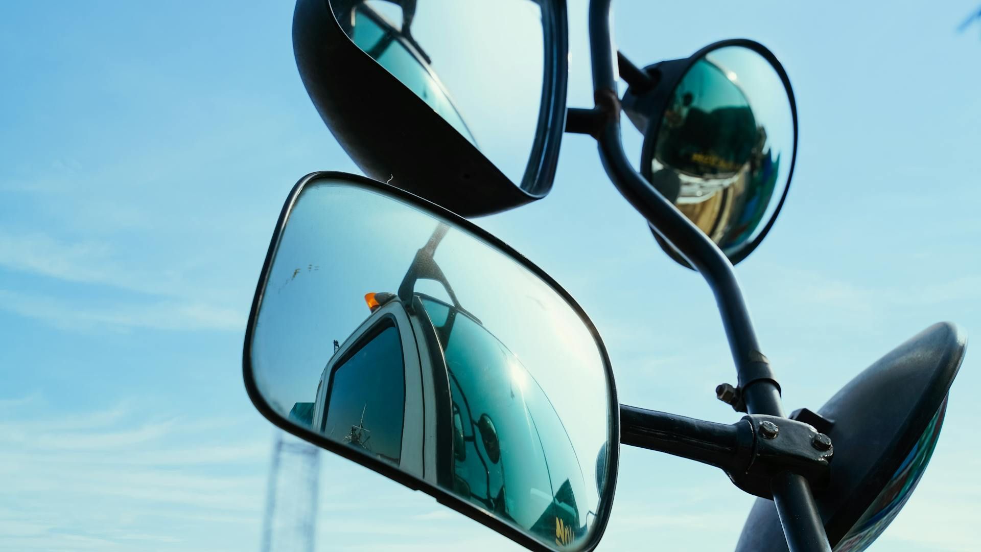 Reflective motorcycle mirrors against a blue sky