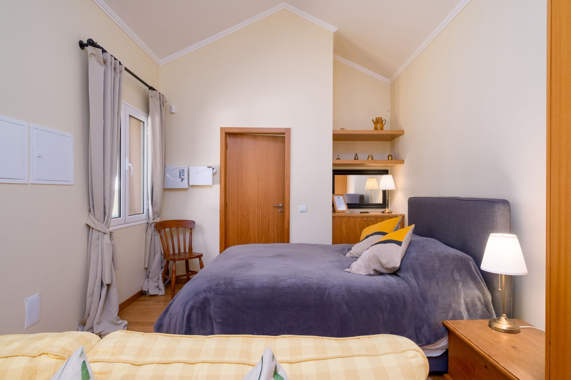 Bedroom with bed, wooden door, window, and small side table with lamp.