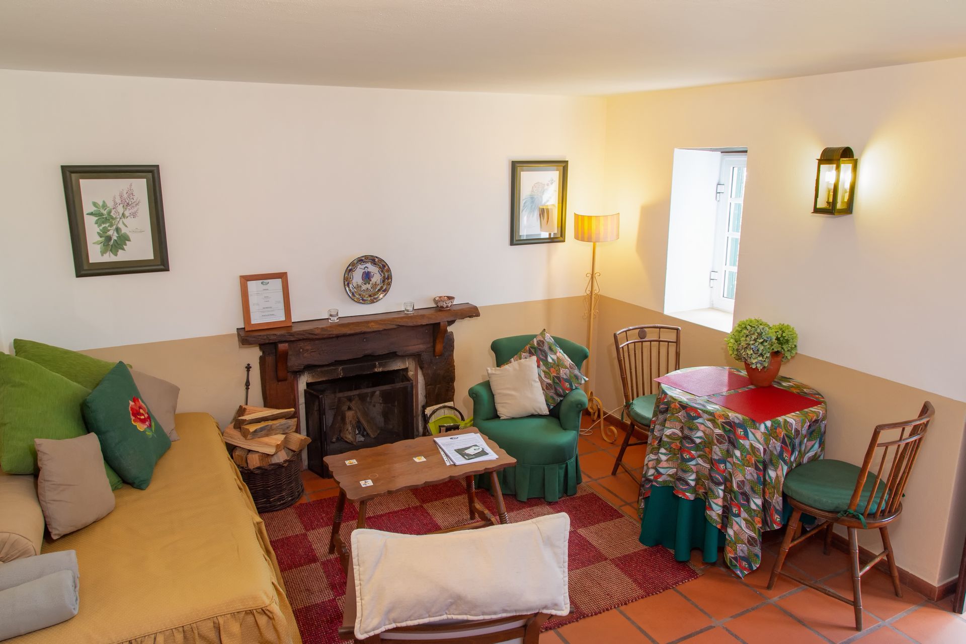 Cozy living room with fireplace, sofa, armchair, small table, and round table set for two.
