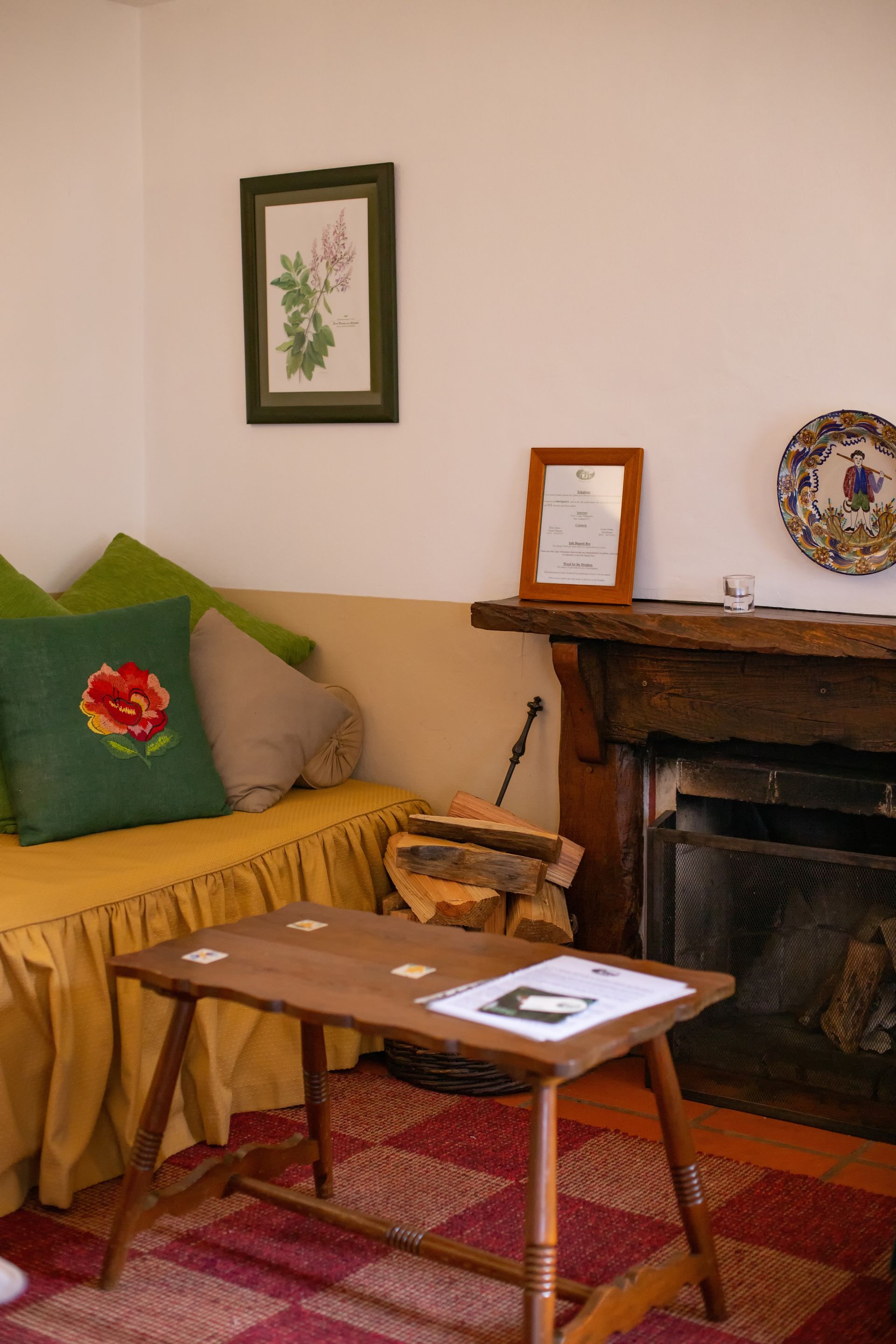 Cozy living room with fireplace, wooden table, couch with pillows, and framed art.