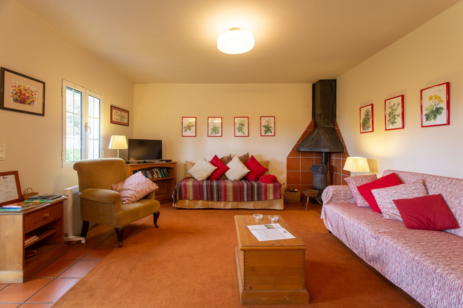 Cozy living room with fireplace, orange rug, two sofas, armchair, and floral artwork.