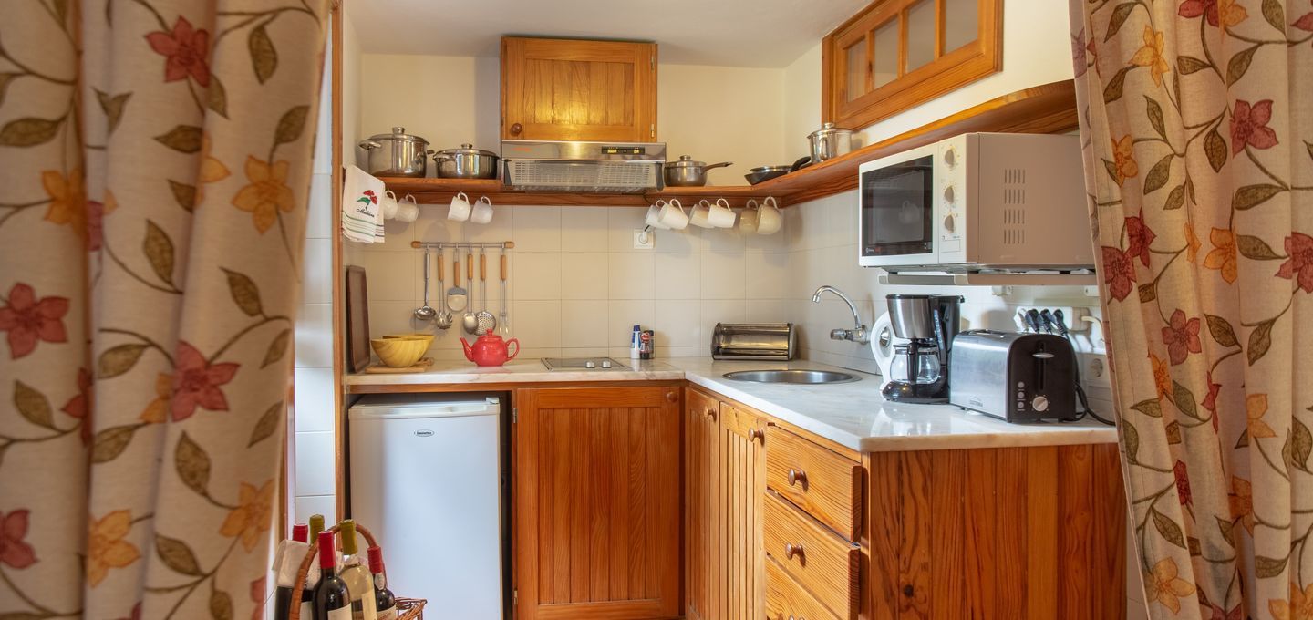 Small kitchen with wood cabinets, white appliances, and floral curtains.