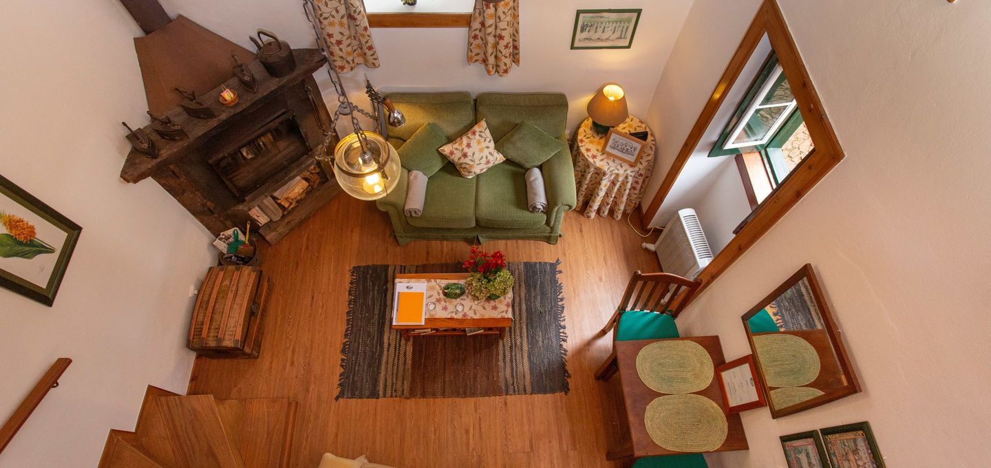 Cozy living room interior with a green sofa, wooden table, fireplace, and stairs.