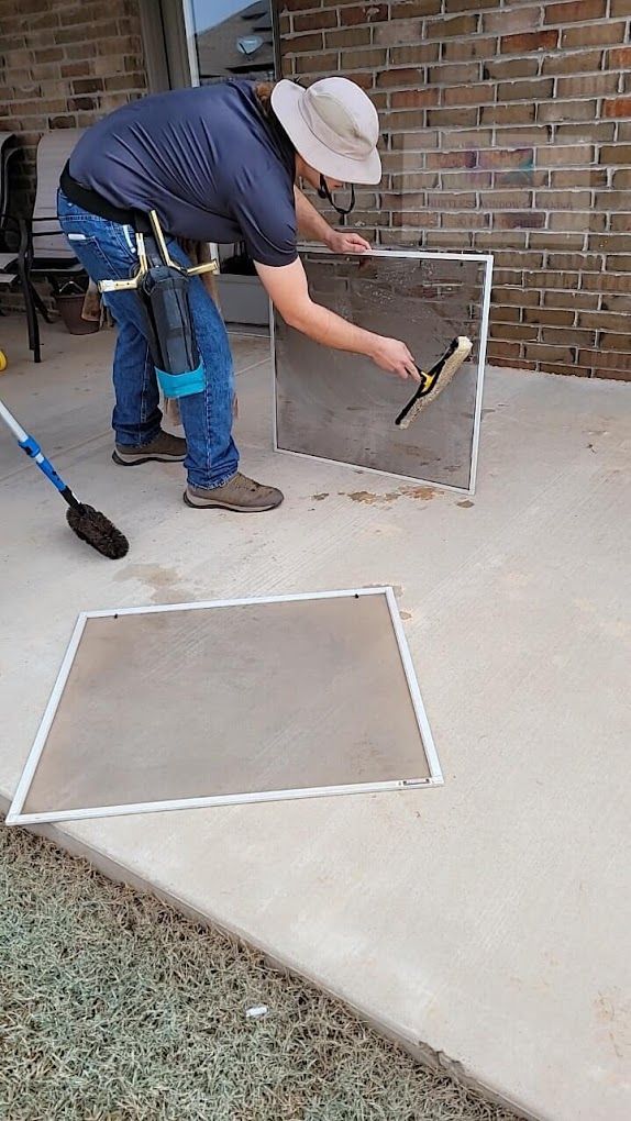 A man is cleaning a window screen with a squeegee.