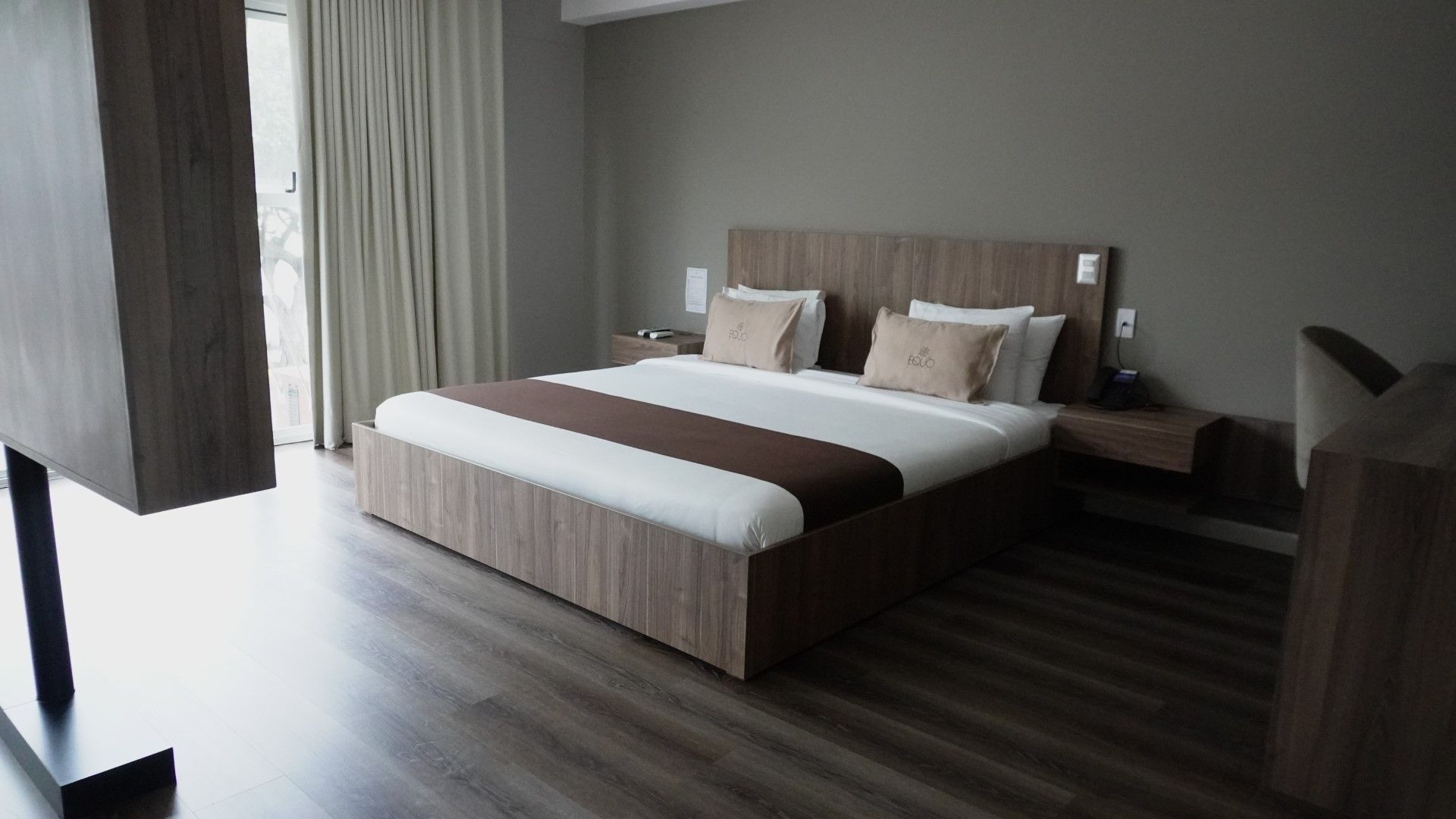 Habitación de hotel con una cama, mesitas de noche y un escritorio contra una pared.