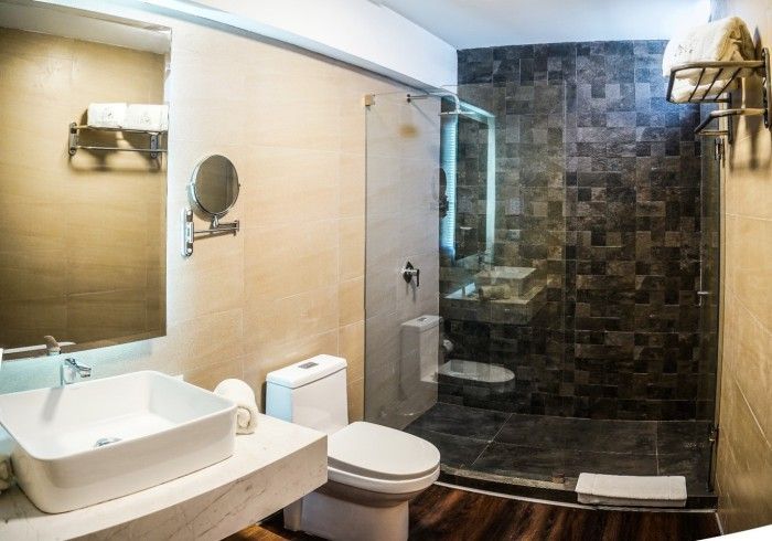 Baño moderno con lavabo, inodoro y ducha con mampara de cristal. Colores tierra.