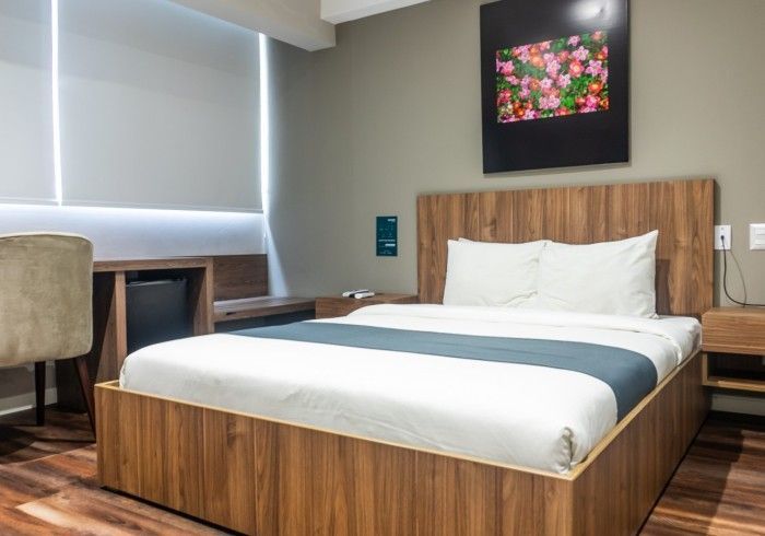 Dormitorio con cama de madera, escritorio y televisor.