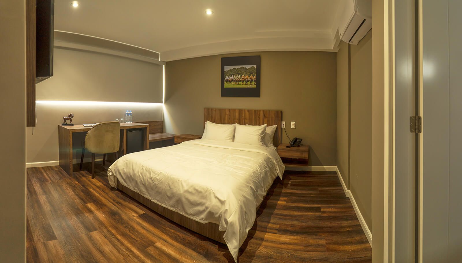 Dormitorio con cama, escritorio, obras de arte y suelo de madera.