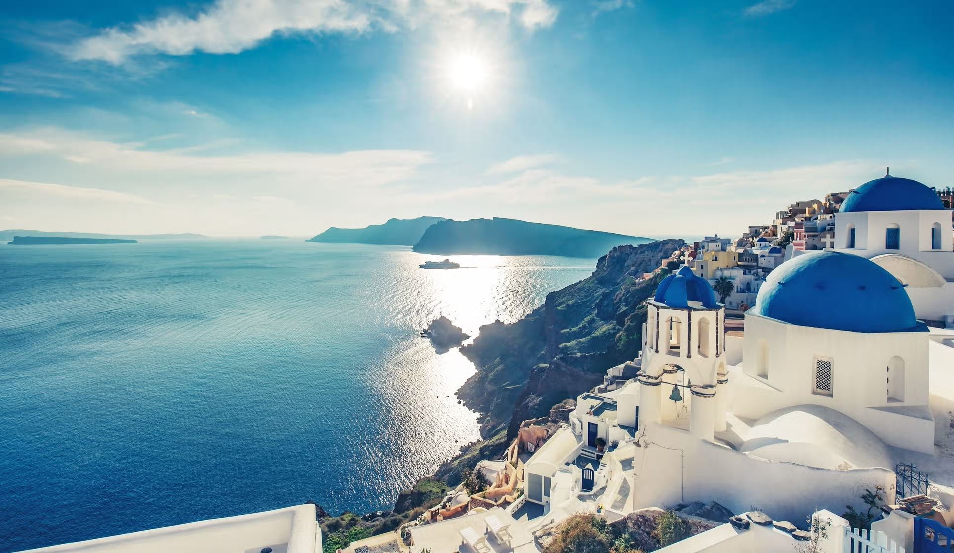 An aerial view of santorini , greece with a blue dome in the middle of the ocean.