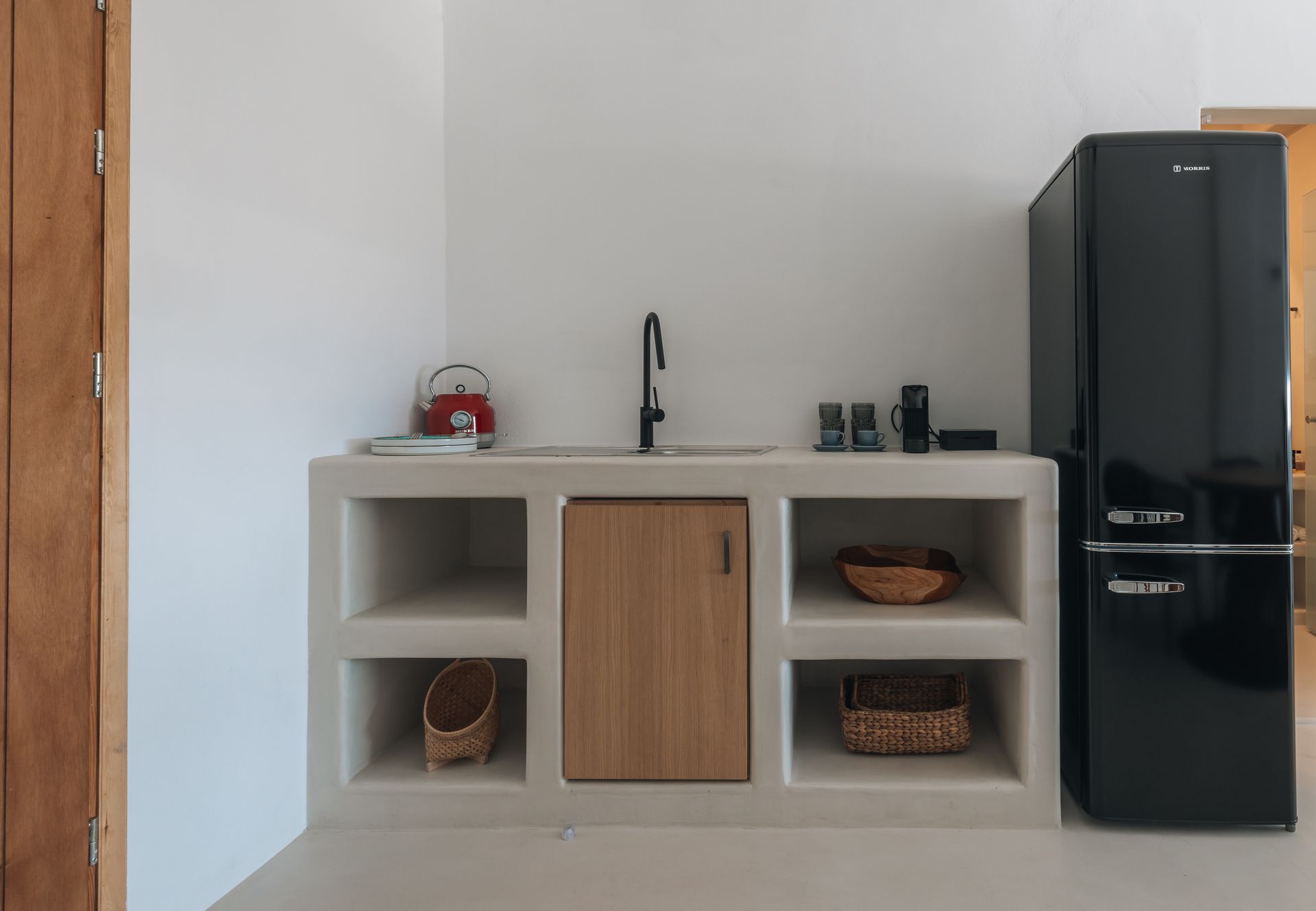A kitchen with a black refrigerator and a sink.