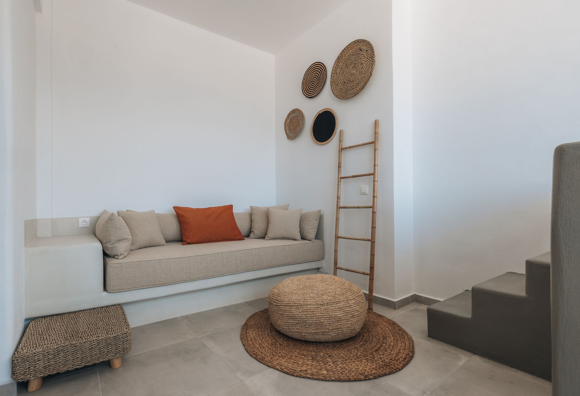 A living room with a couch , ottoman , and stairs.