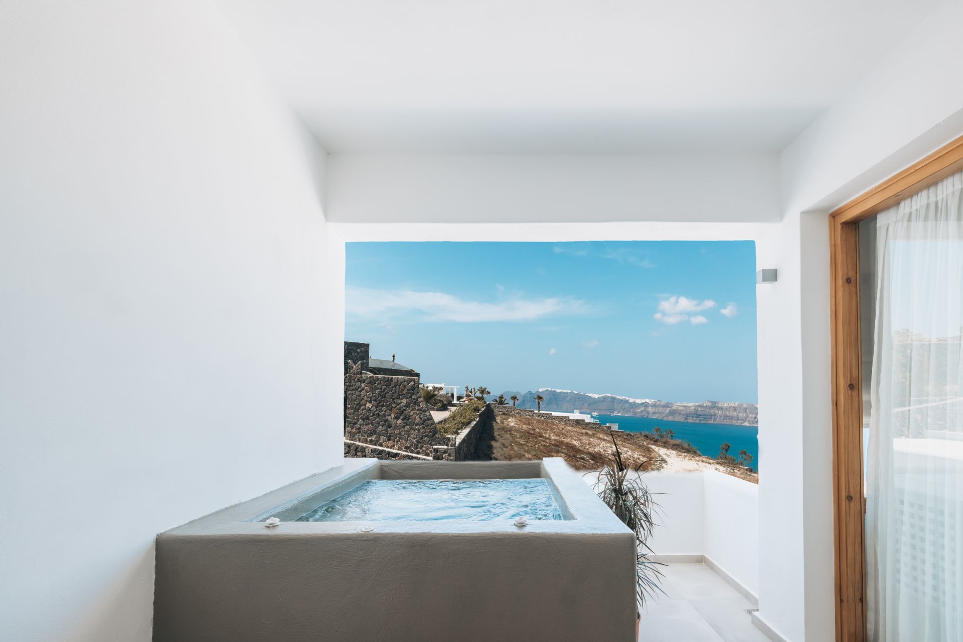 There is a jacuzzi on the balcony with a view of the ocean.