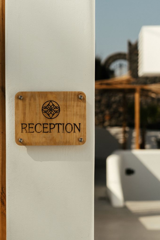 A wooden sign on a white wall that says reception