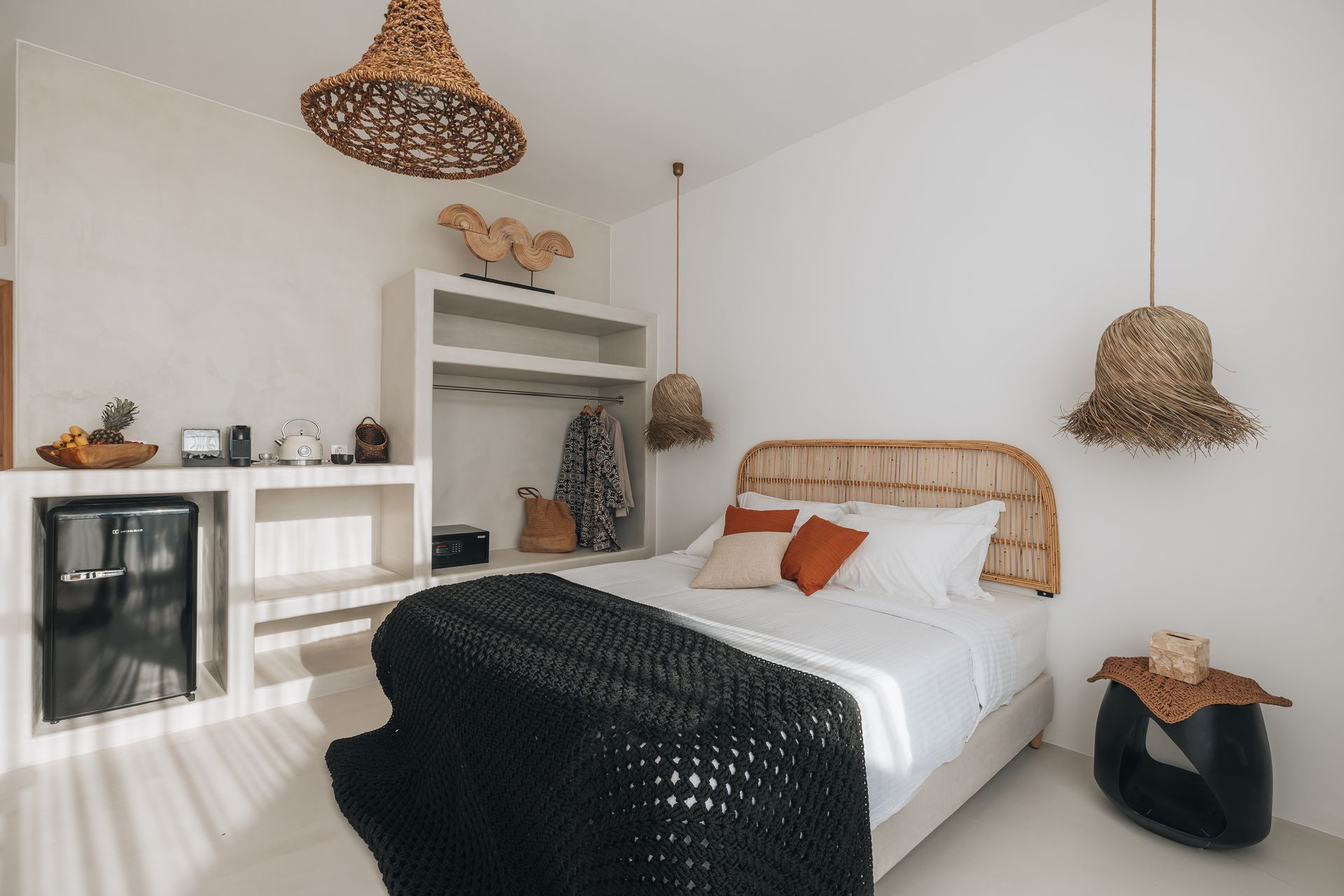 There is a bed in the middle of the room with a wicker headboard.