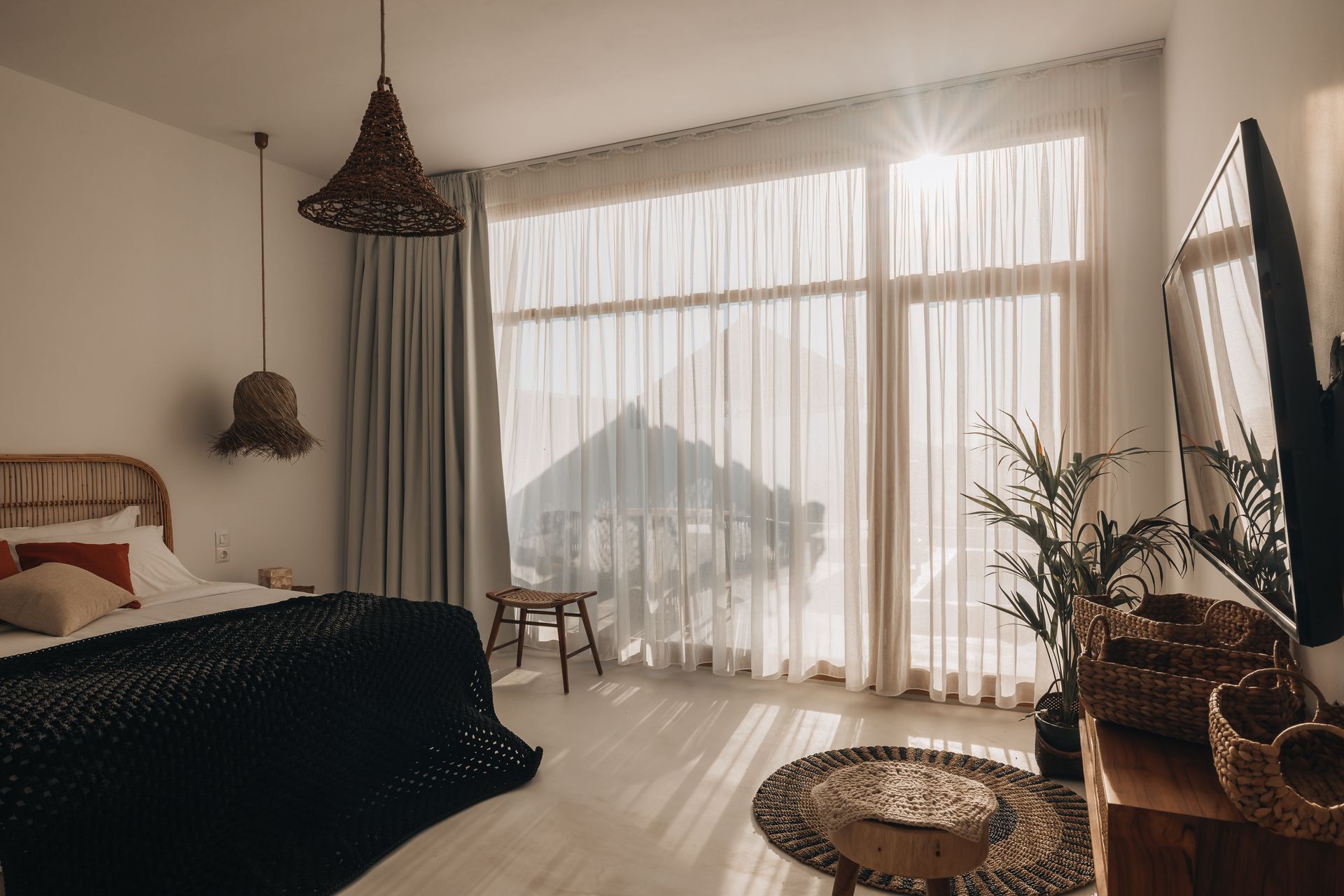 A bedroom with a large window and a bed.
