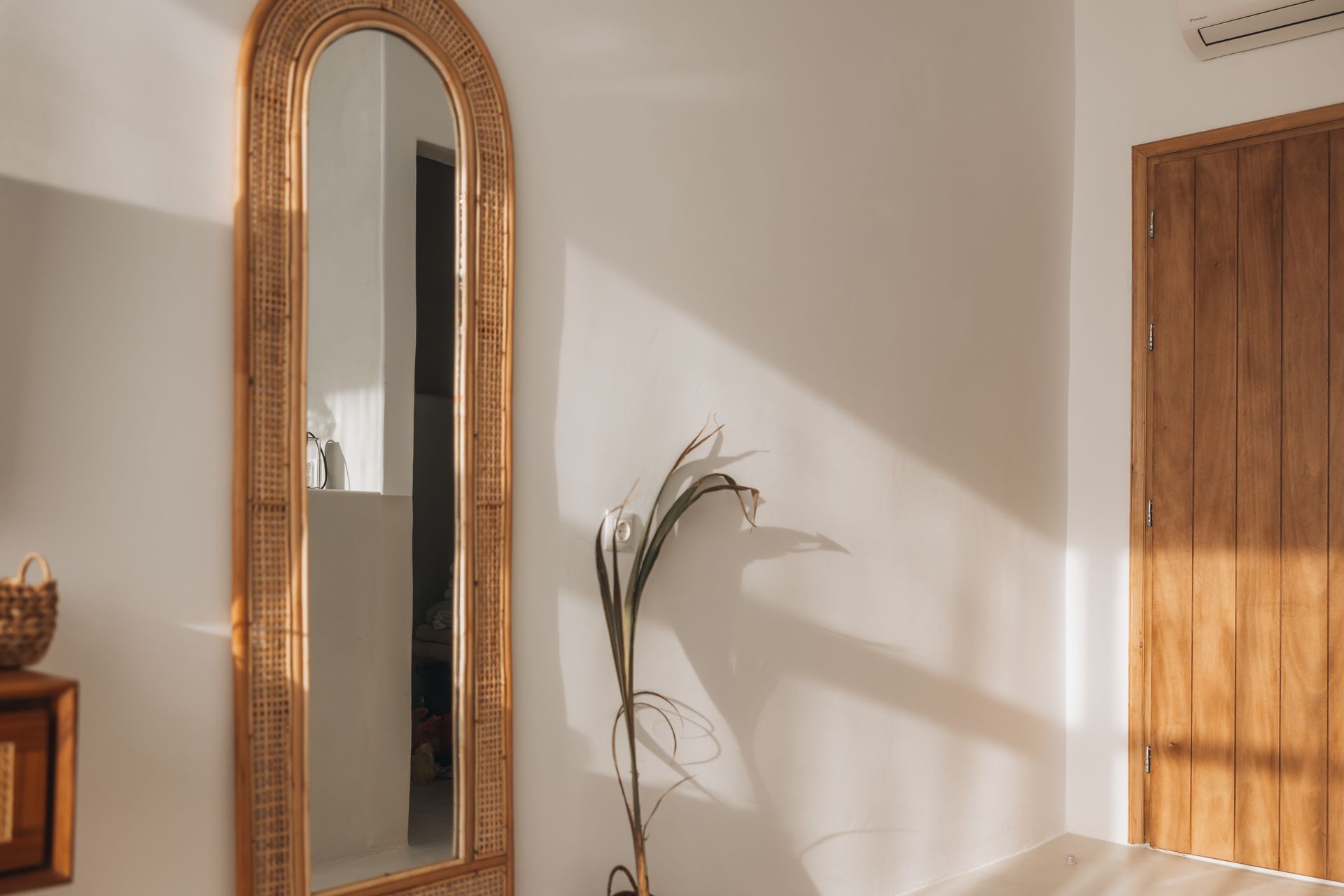 A full length mirror is hanging on a white wall in a room.