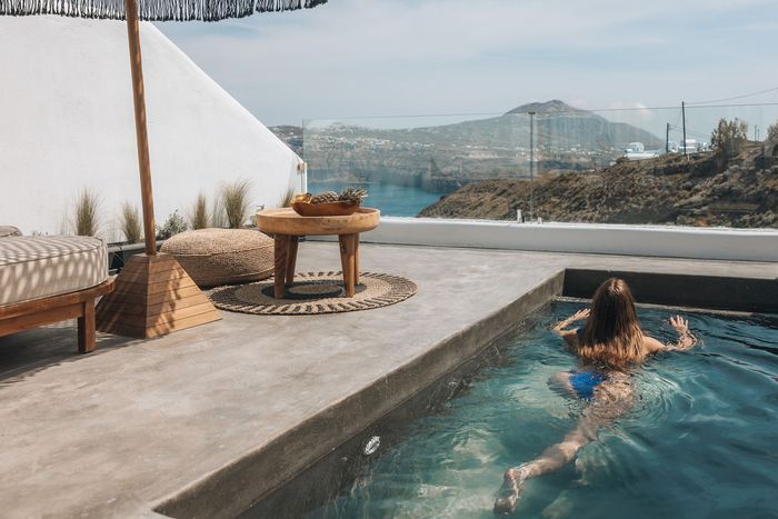 A woman is laying in a swimming pool with a view of the ocean.