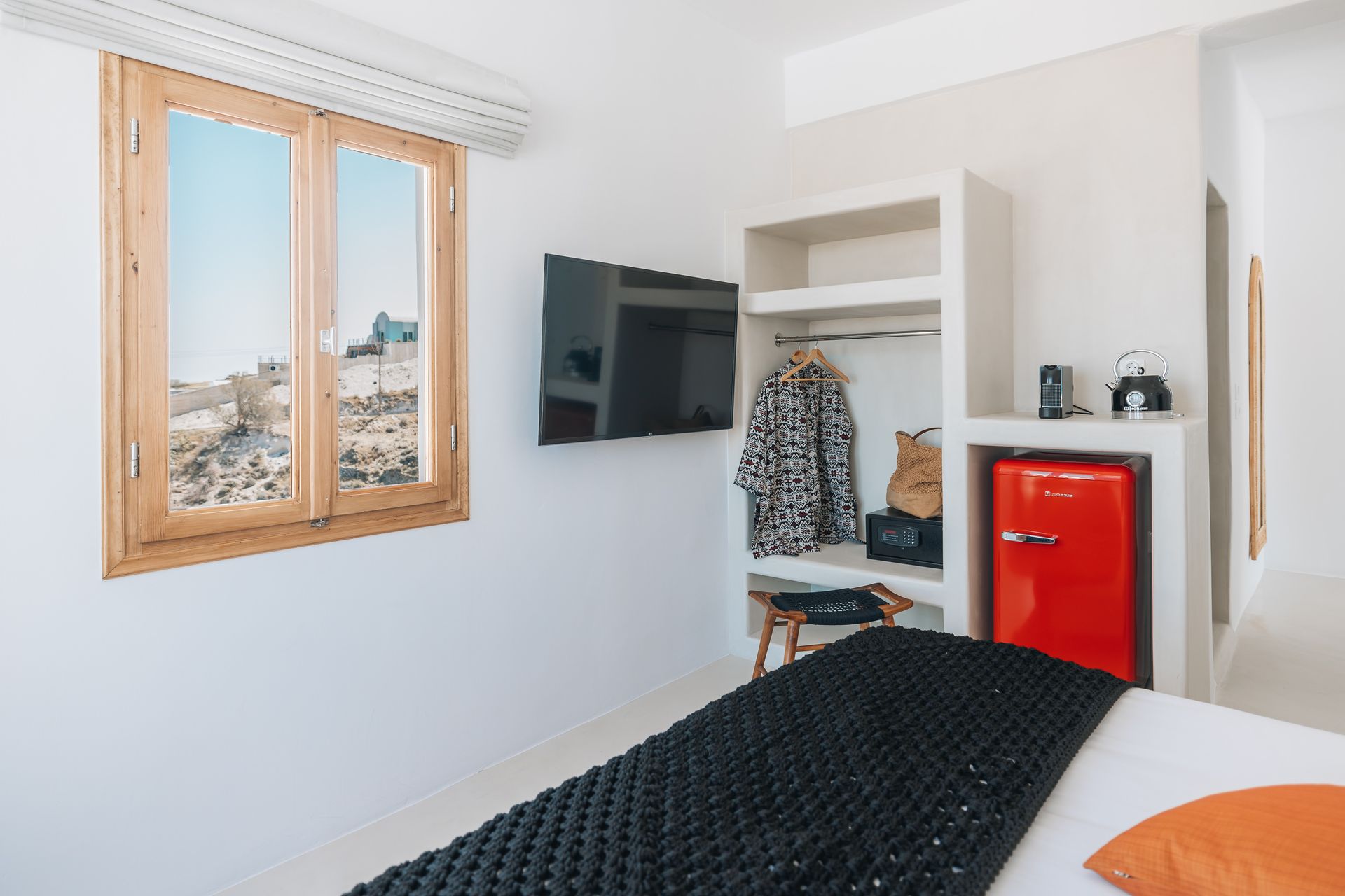 A hotel room with a bed , television , refrigerator and window.
