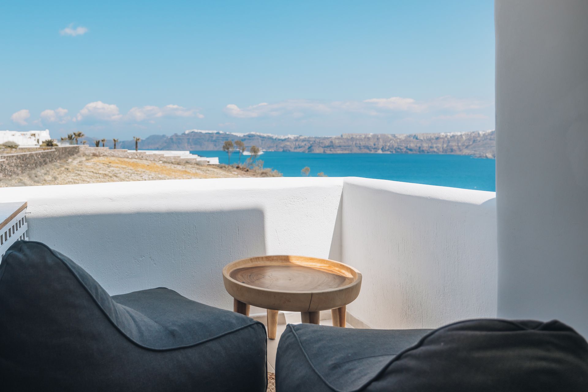 There is a table and chairs on the balcony with a view of the ocean.