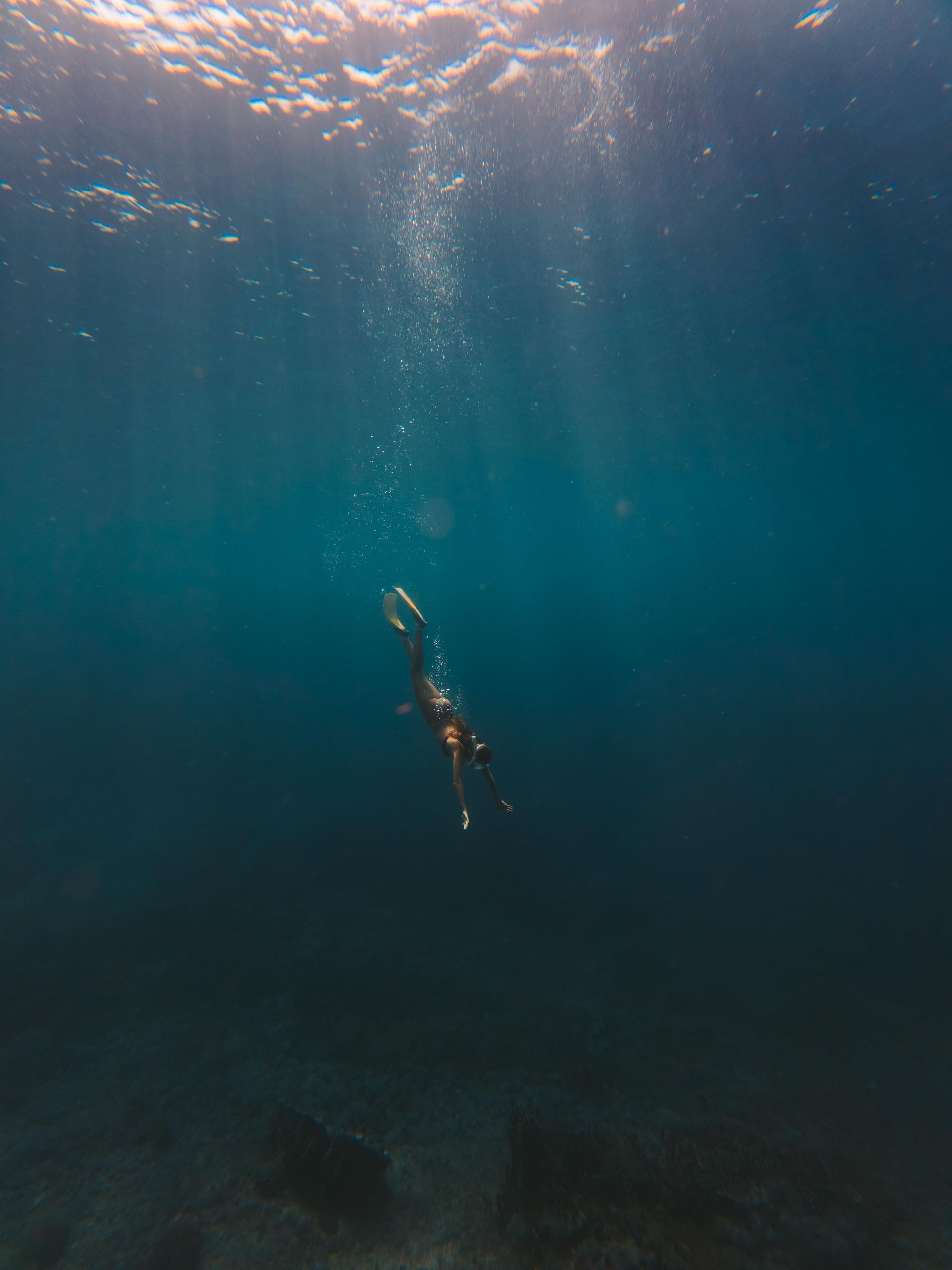 A person is swimming in the ocean with bubbles coming out of the water.
