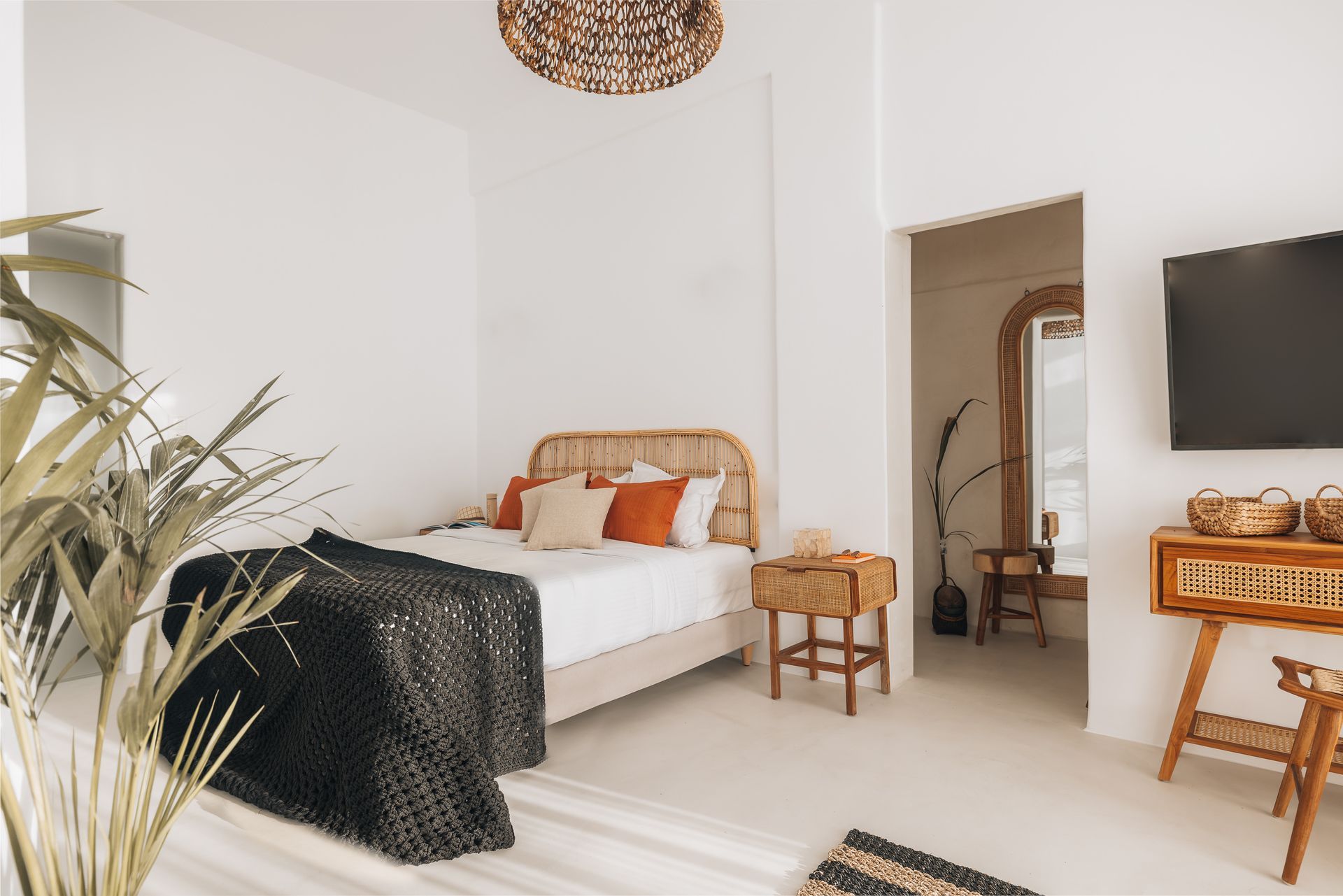 A bedroom with a bed , nightstand , television and a wicker headboard.
