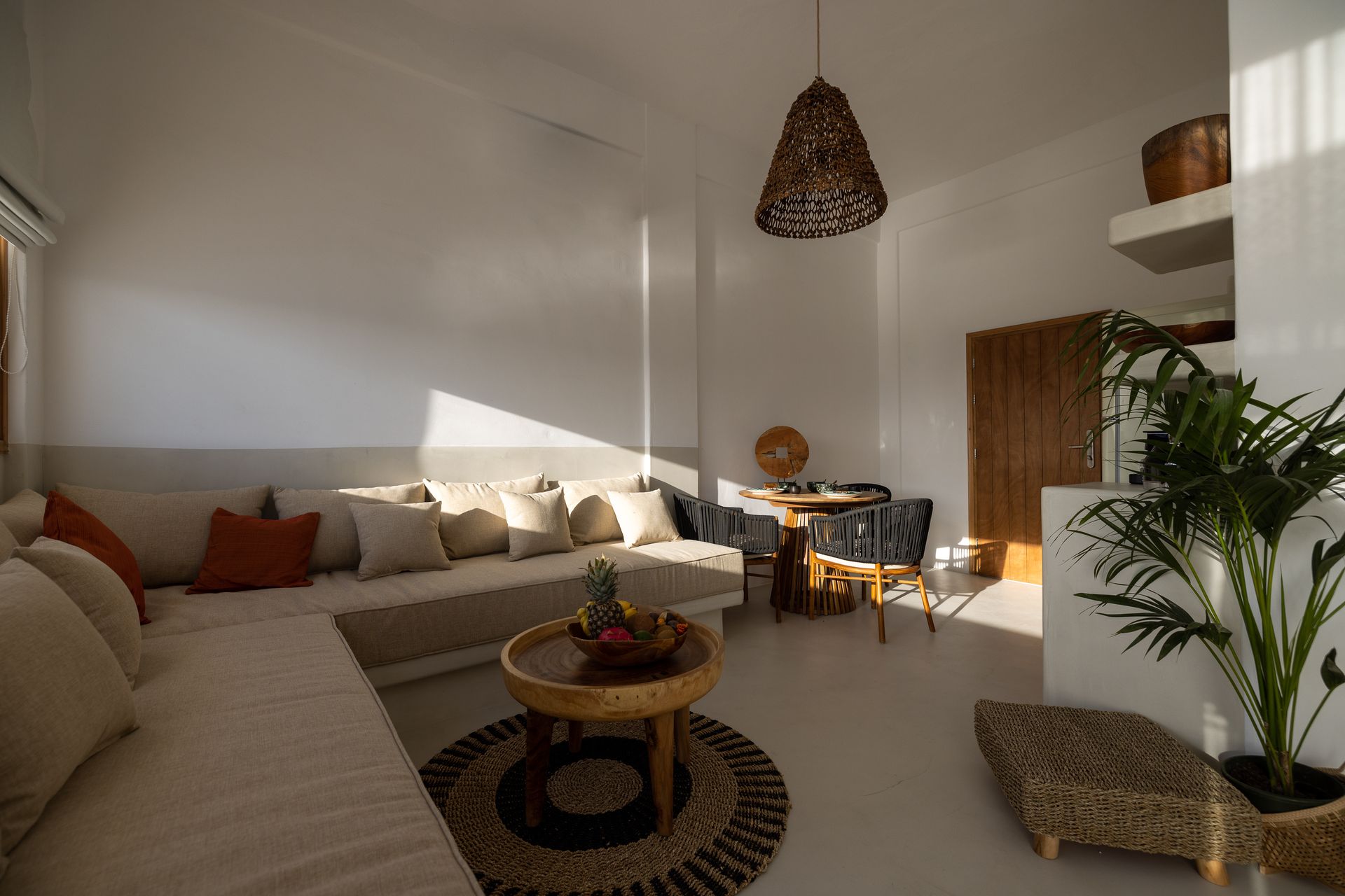 A living room with a couch , table , chairs and a plant.
