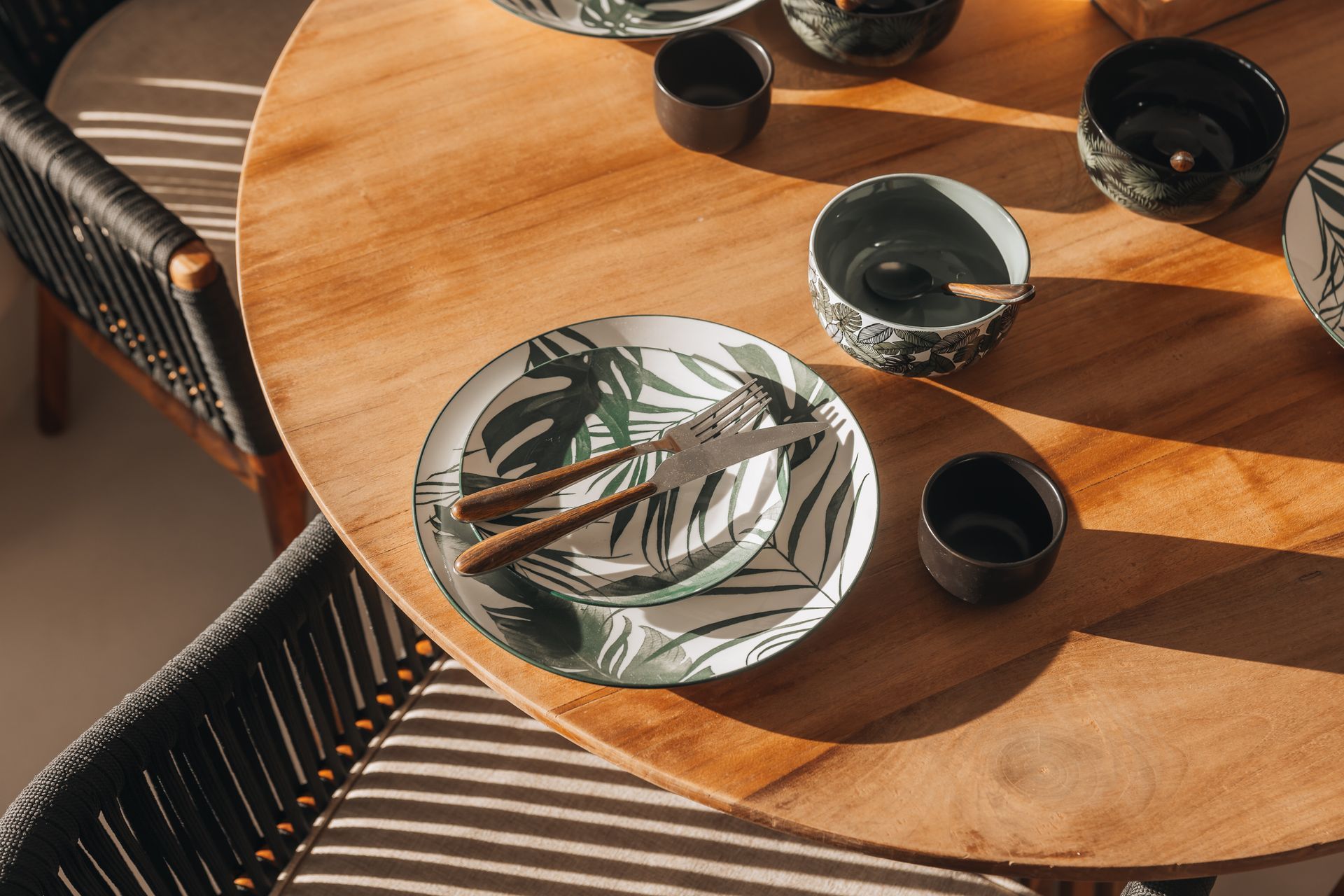 A wooden table with plates , bowls and chopsticks on it.