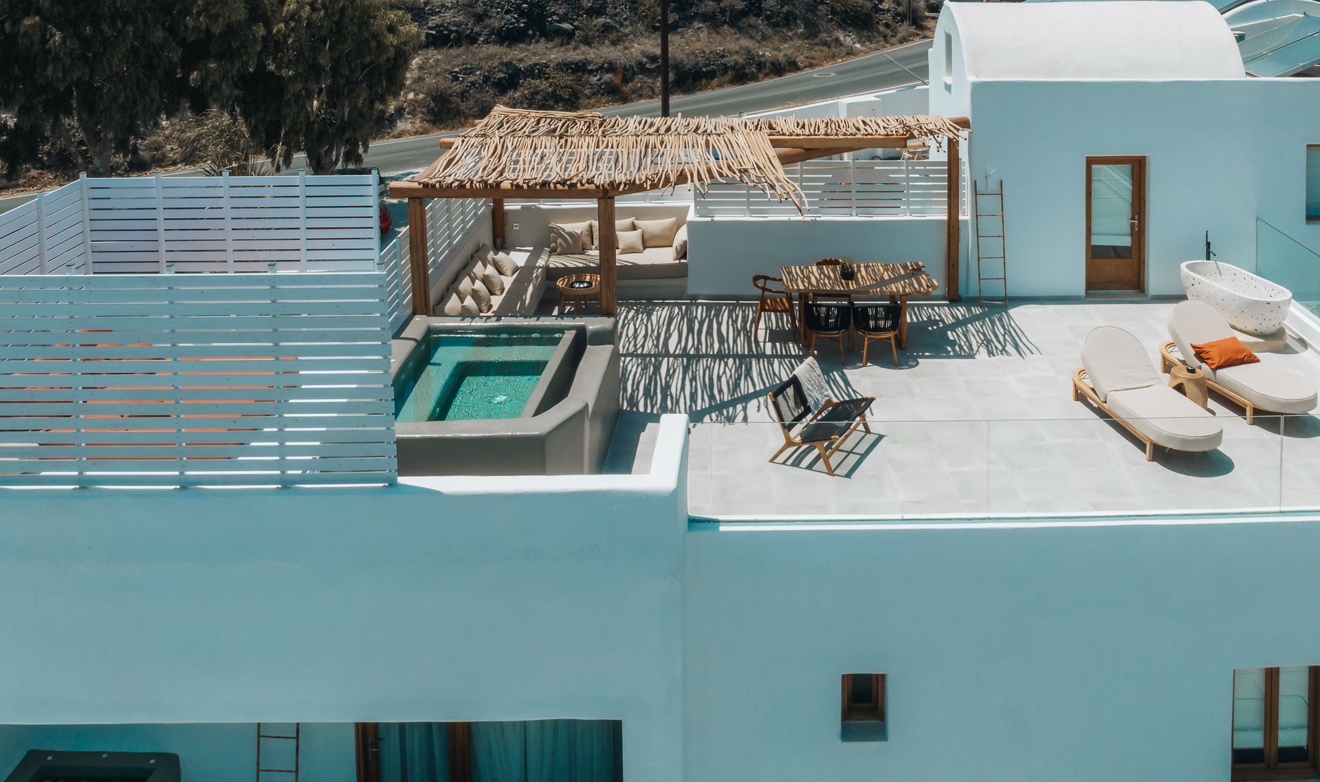 An aerial view of a white house with a pool on the roof.