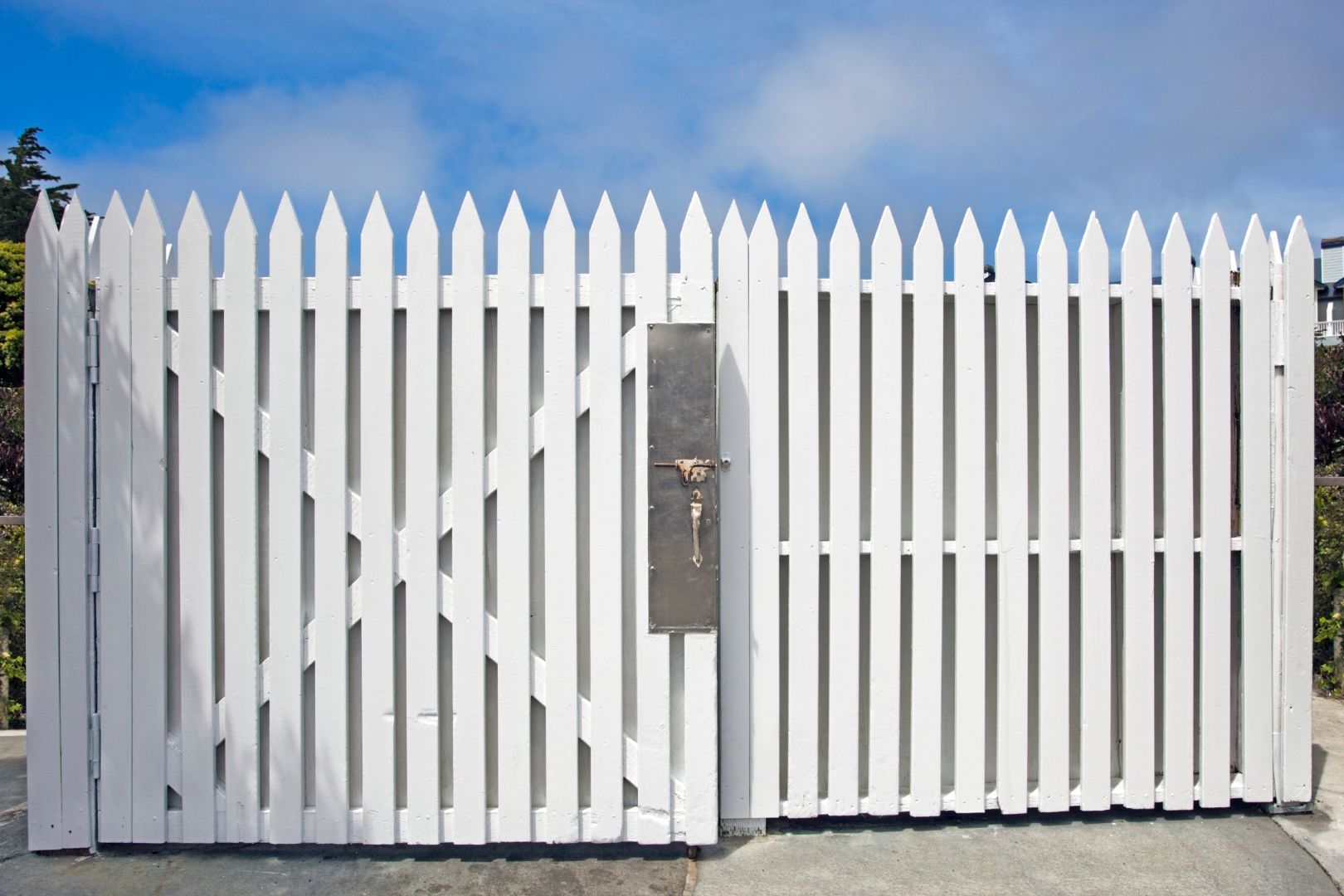 An image of a white picket fence with a heavy duty lock on the gate