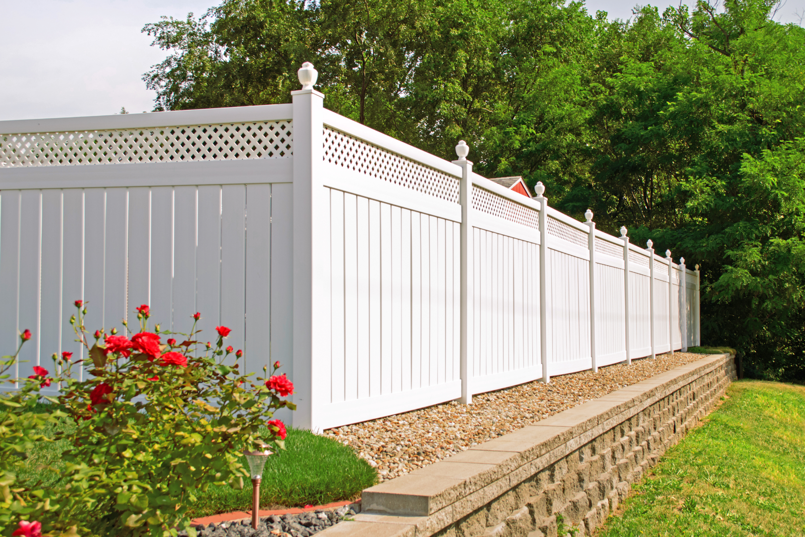 An image of a white vinyl Privacy Fence with decorative top trim with a raised gravel pad in Kent, OH