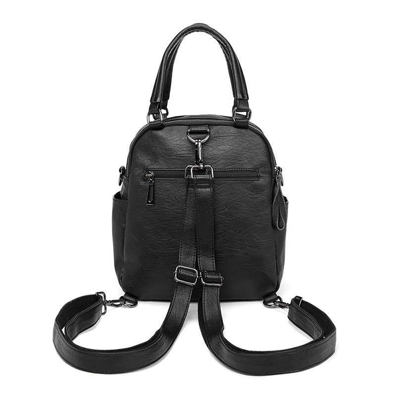 Mochila de piel negra con asas superiores y correa de hombro a rayas.