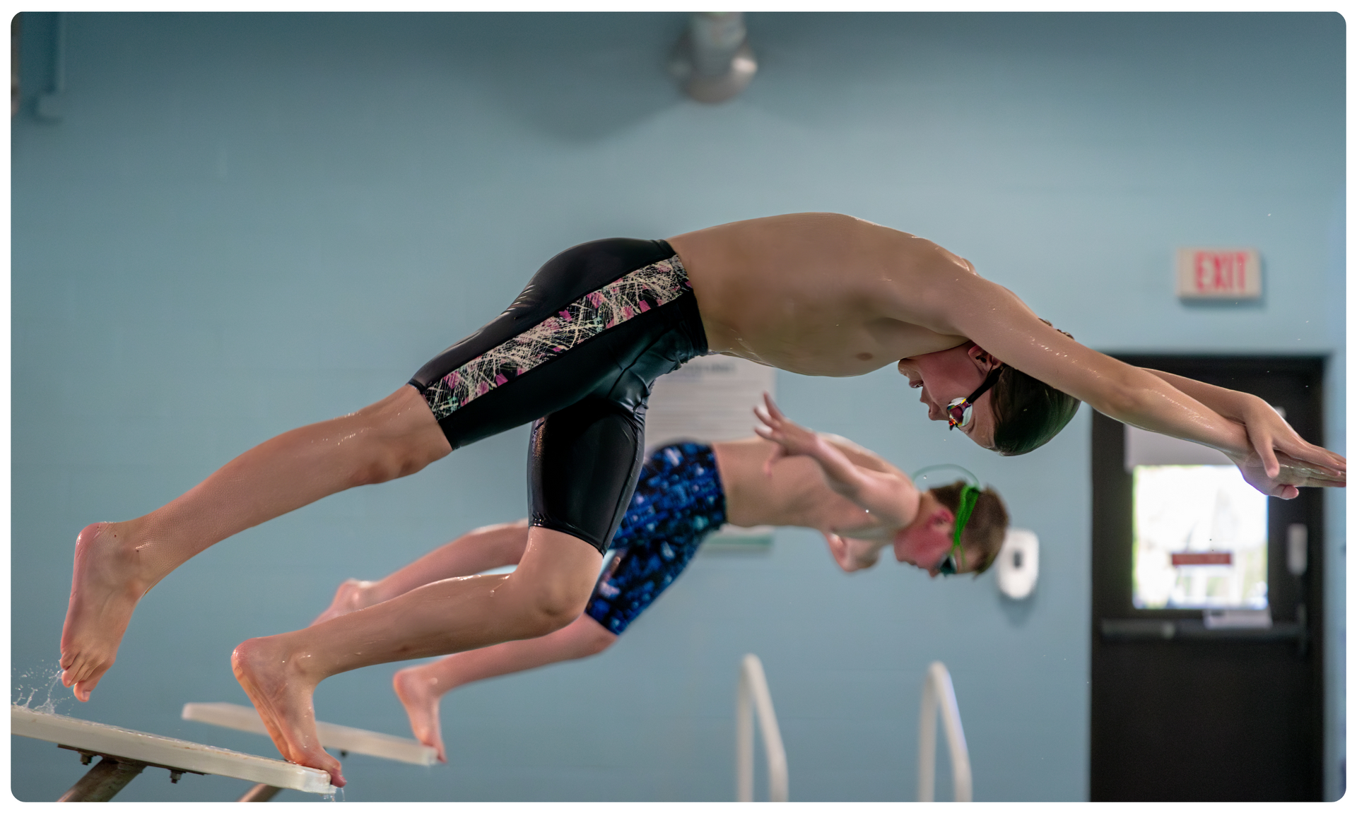 young men diving into pool for race
