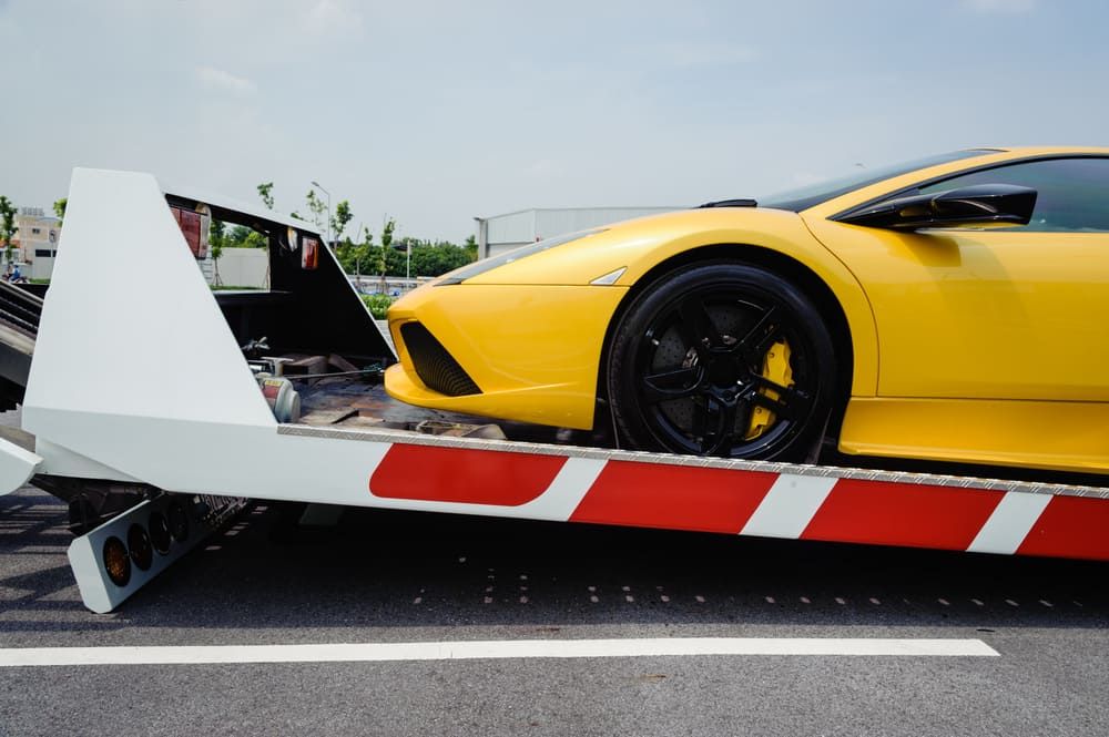 A Yellow Sports Car Is Being Towed By A Tow Truck — Wilson's Towing In Kilcoy, QLD