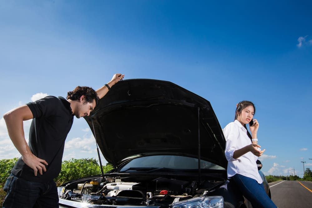 A Man And A Woman Are Looking Under The Hood Of A Broken Down Car — Wilson's Towing In Highfields, QLD