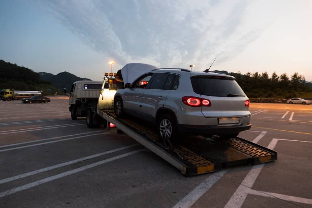 A Car Is Being Towed By A Tow Truck In A Parking Lot — Wilson's Towing In Pittsworth, QLD